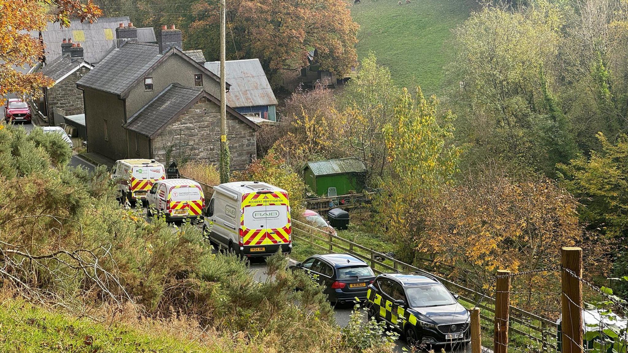 Emergency vehicles near the scene of the rail collision, with buildings nearby and fields and trees also visible 