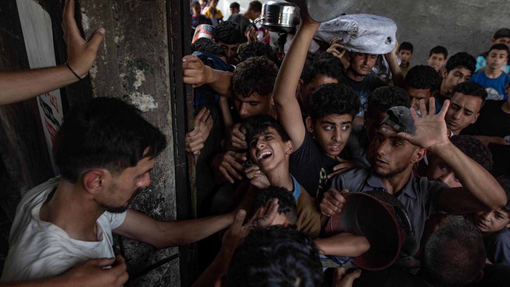 Hundreds of internally displaced Palestinians gather outside a charity kitchen in Gaza City to receive food, in northern Gaza (18 May 2025)