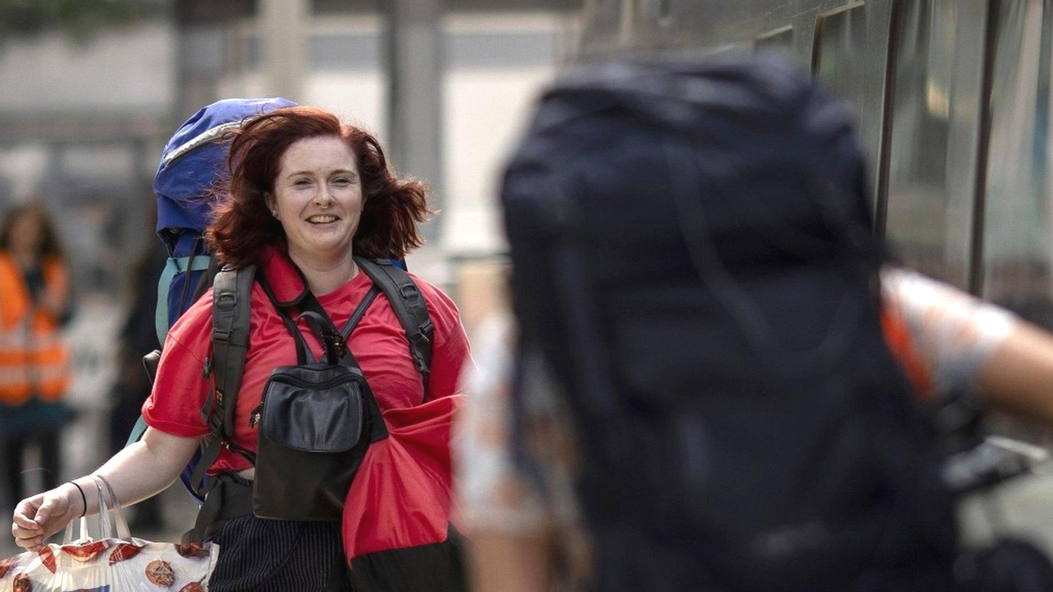 Two passengers with rucksacks about to board a train towards Glastonbury