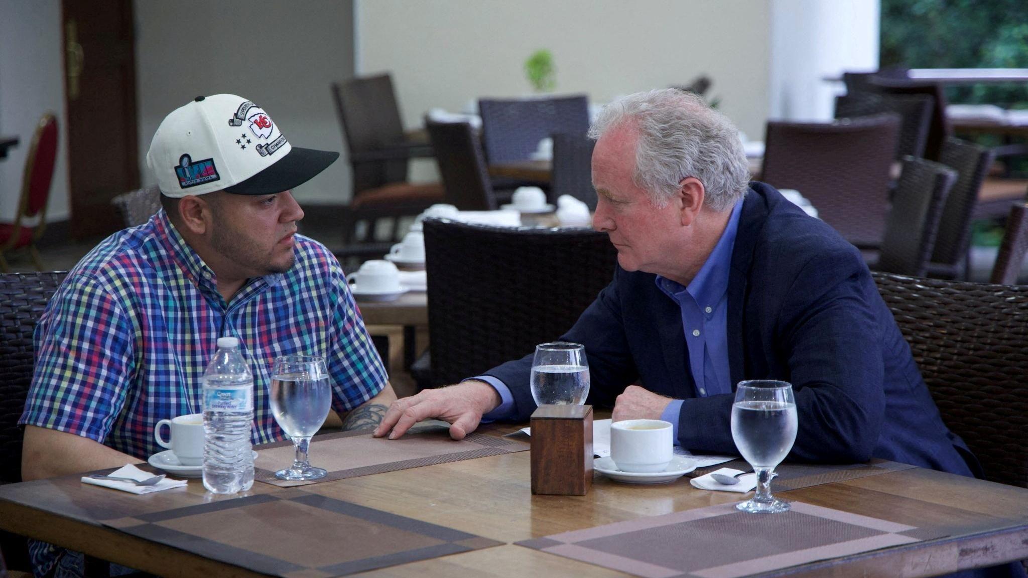 Kilmar Abrego Garcia speaking with Senator Chris Van Hollen at a table with glasses of water in front