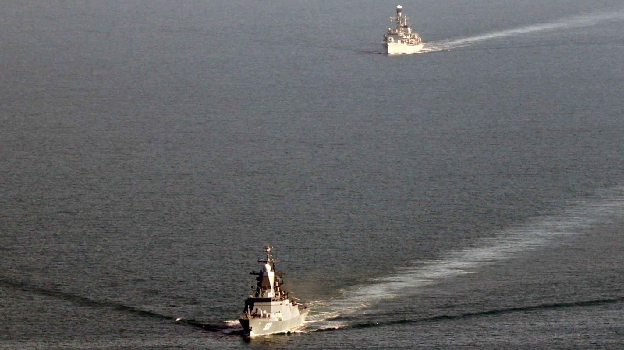 Two ships, one following the other, are seen on the sea.