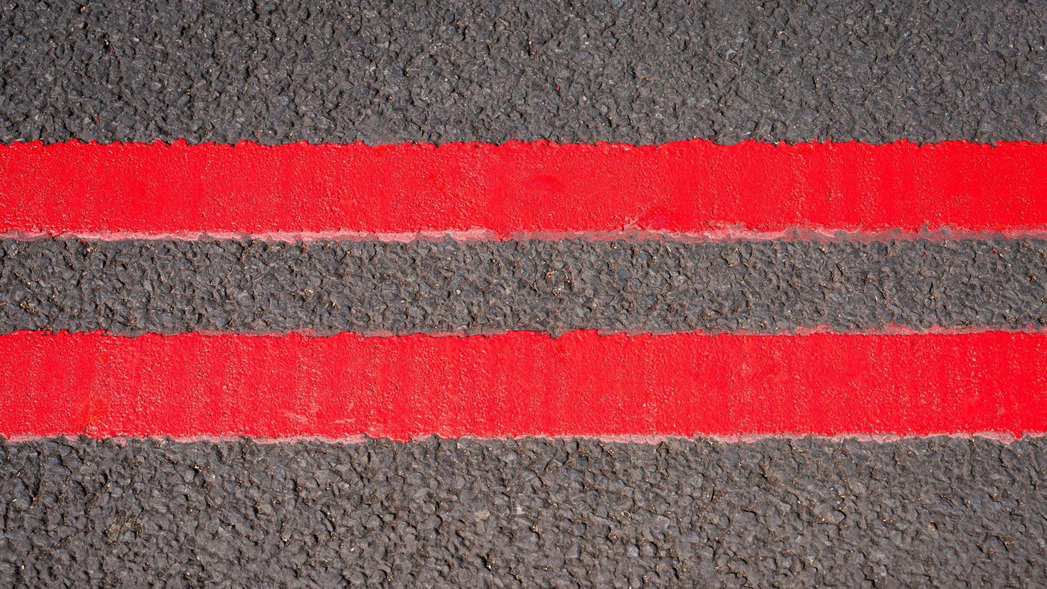 Two striking red lines on the side of a road. 