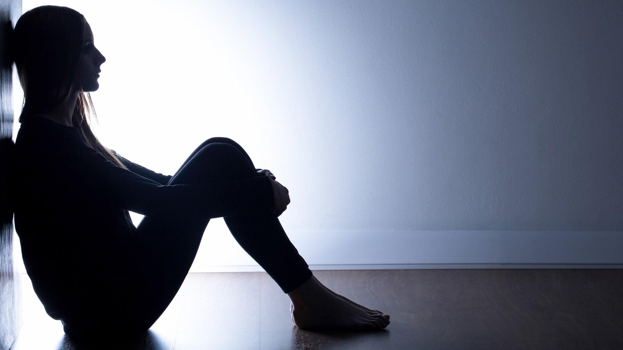 Teenage girl sitting alone in dark room