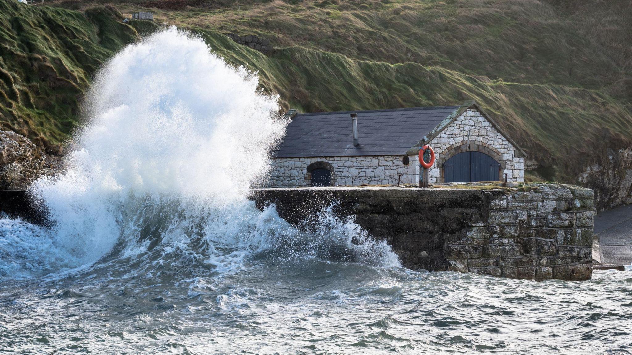A large wave crashes against a wall in Ballintoy
