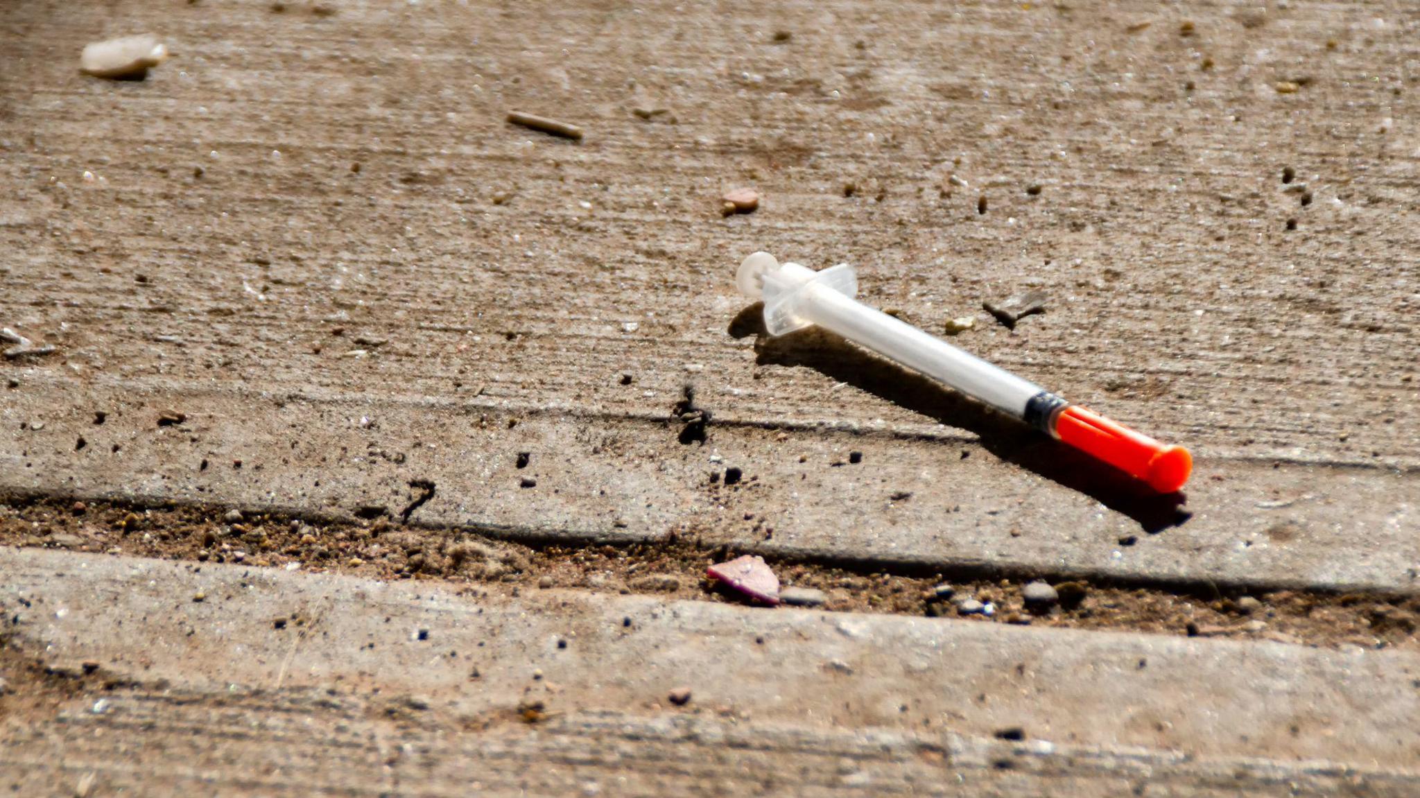 A used needle is discarded on the ground.