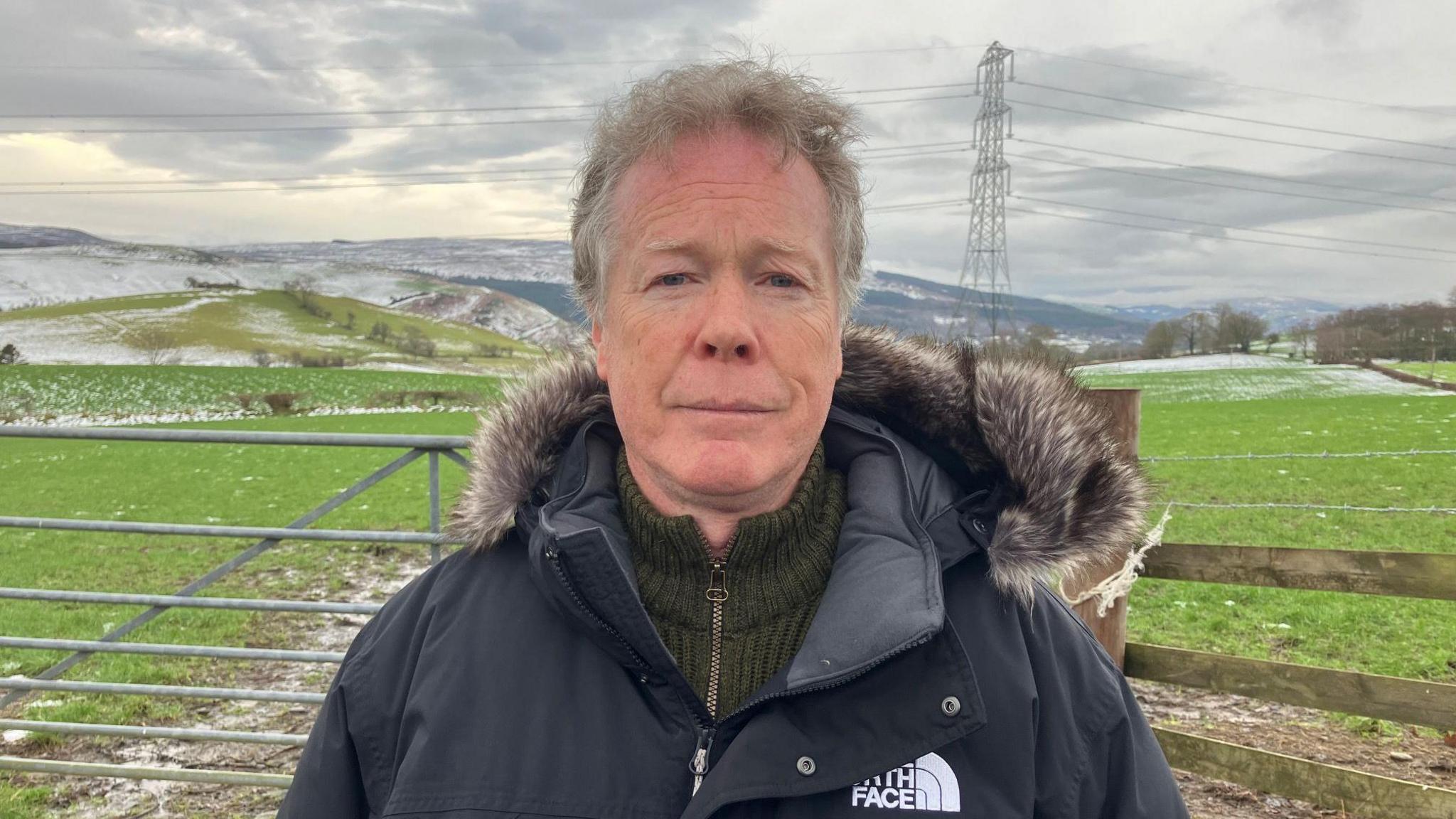 Kevin Sharp looking into the camera with the proposed Battery Energy Storage Systems site behind him. 