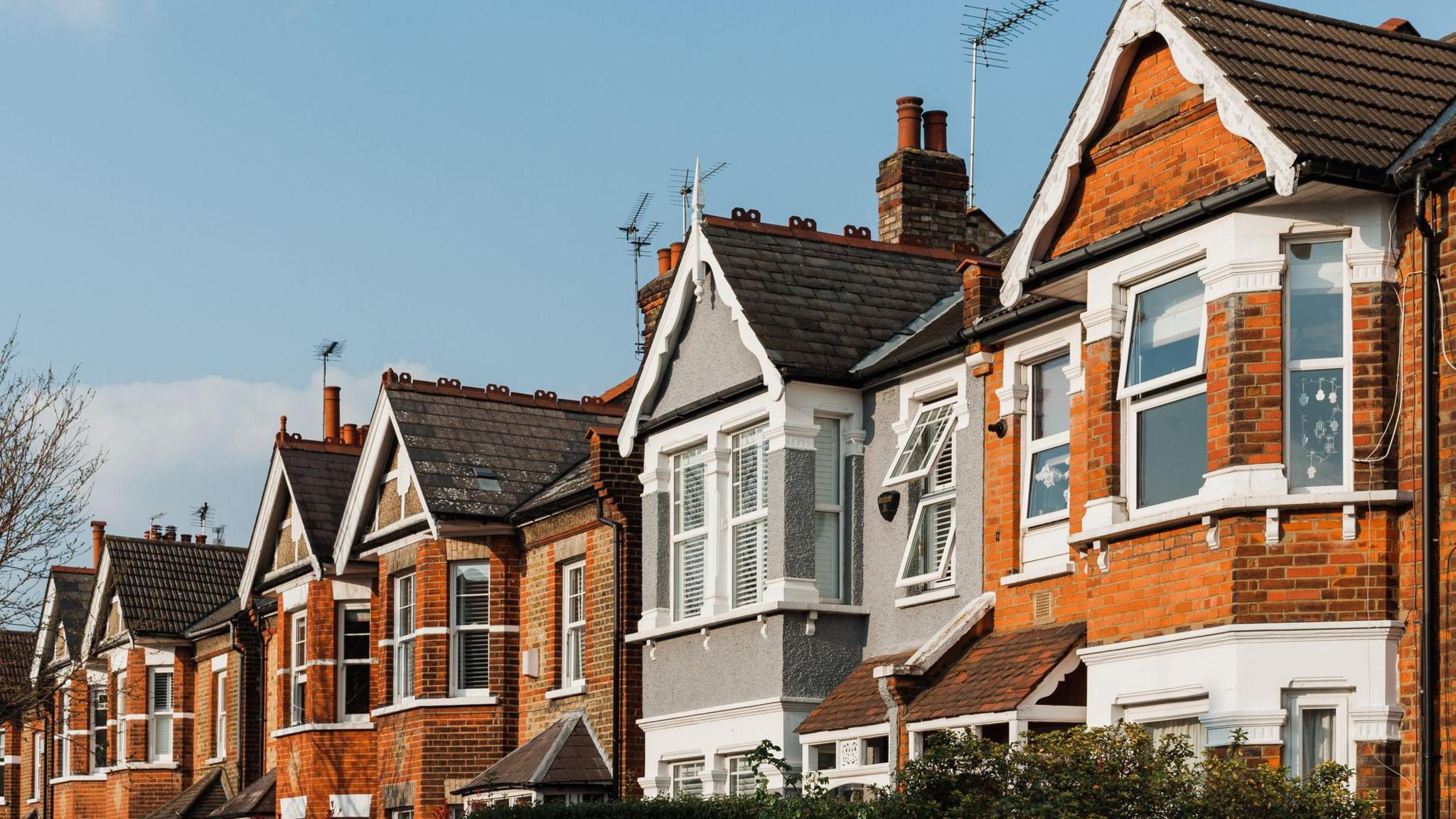 A row of terraced brick houses underneath a blue sky.