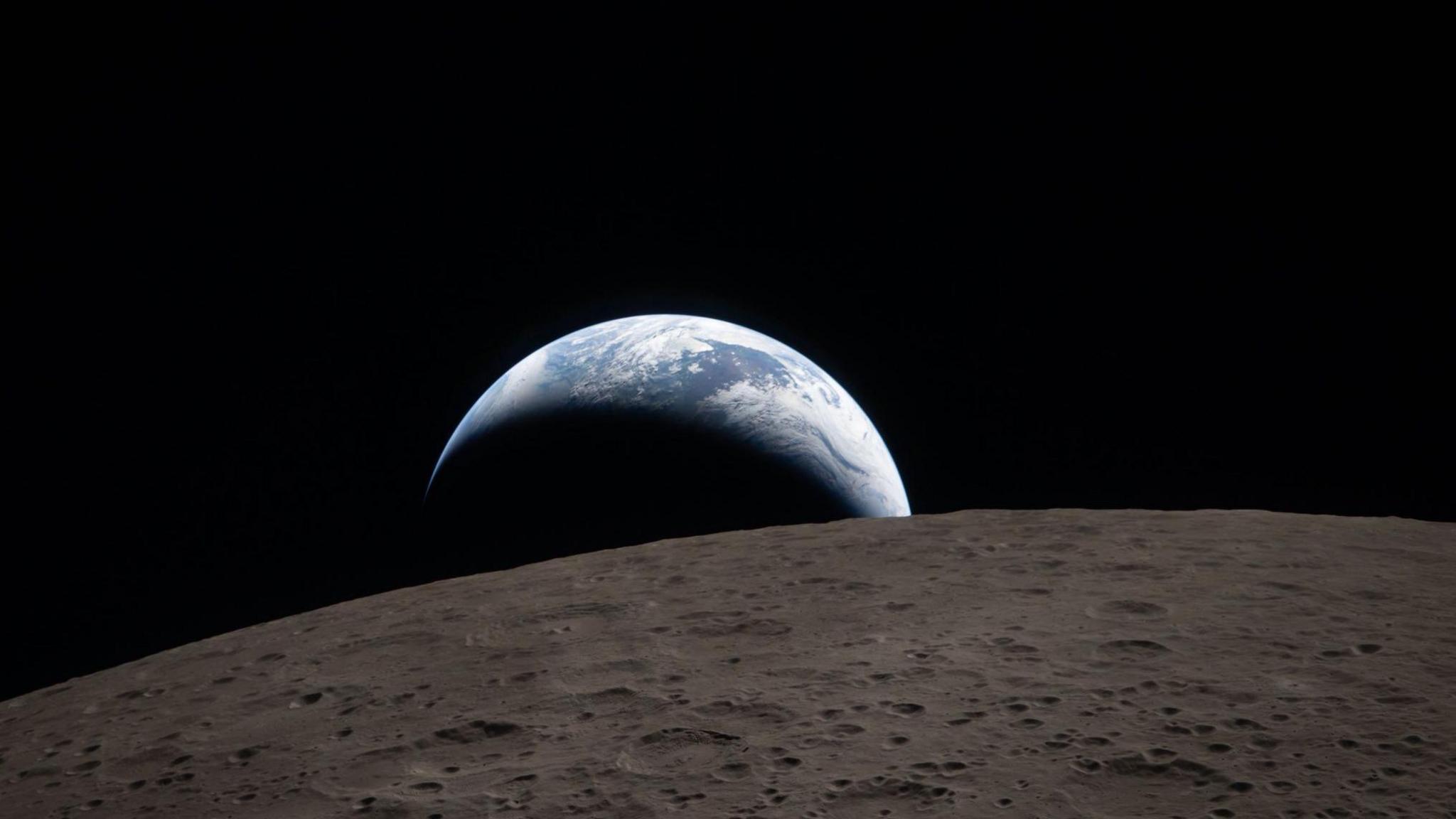 The blue Earth rising above the brownish grey surface