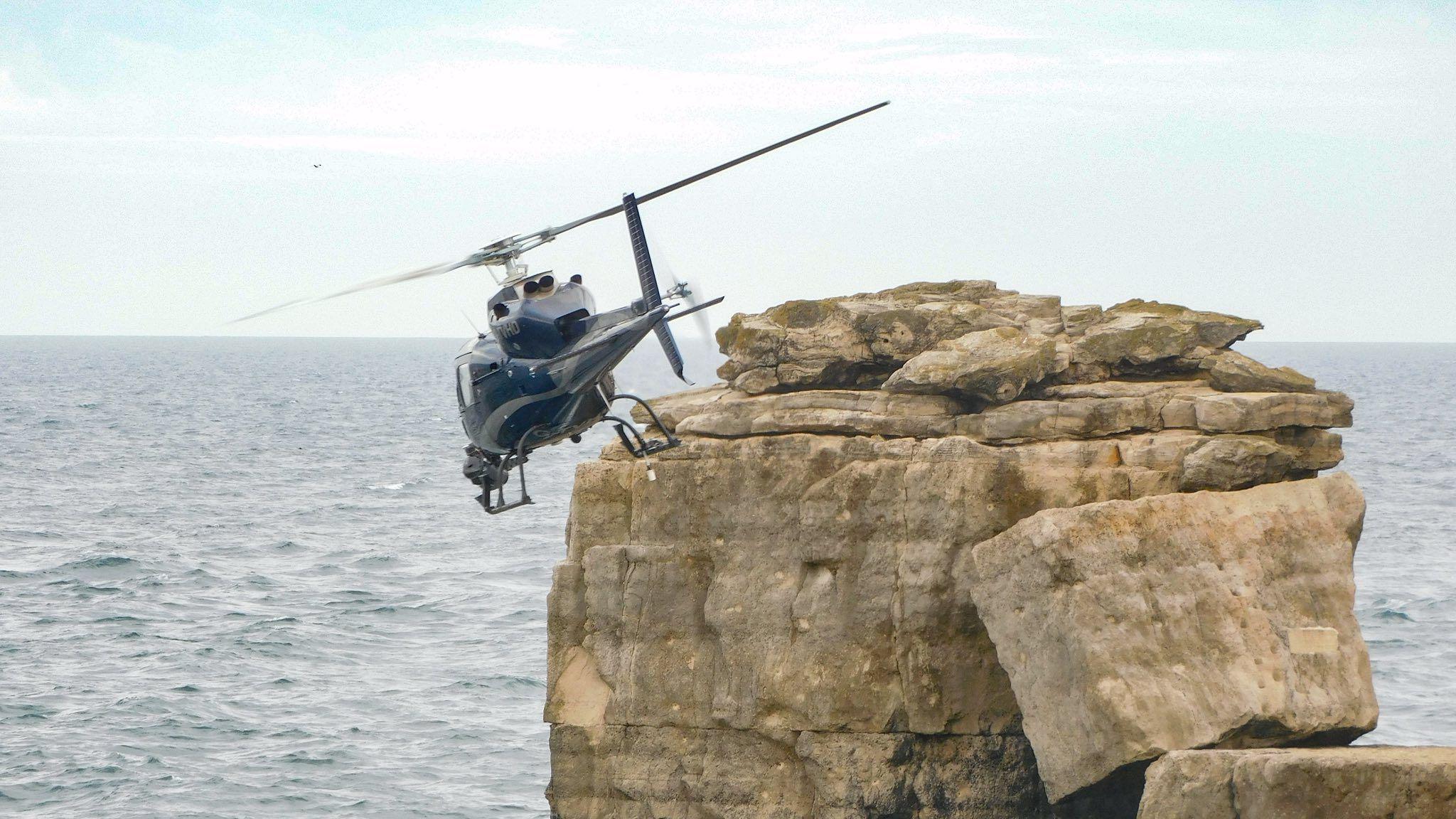 A helicopter flying over Pulpit Rock. The weather is overcast.