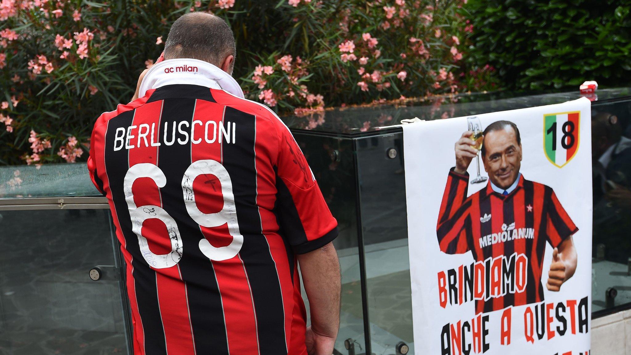 A supporter of the AC Milan football club wears a jersey of the honorary president of the club Silvio Berlusconi