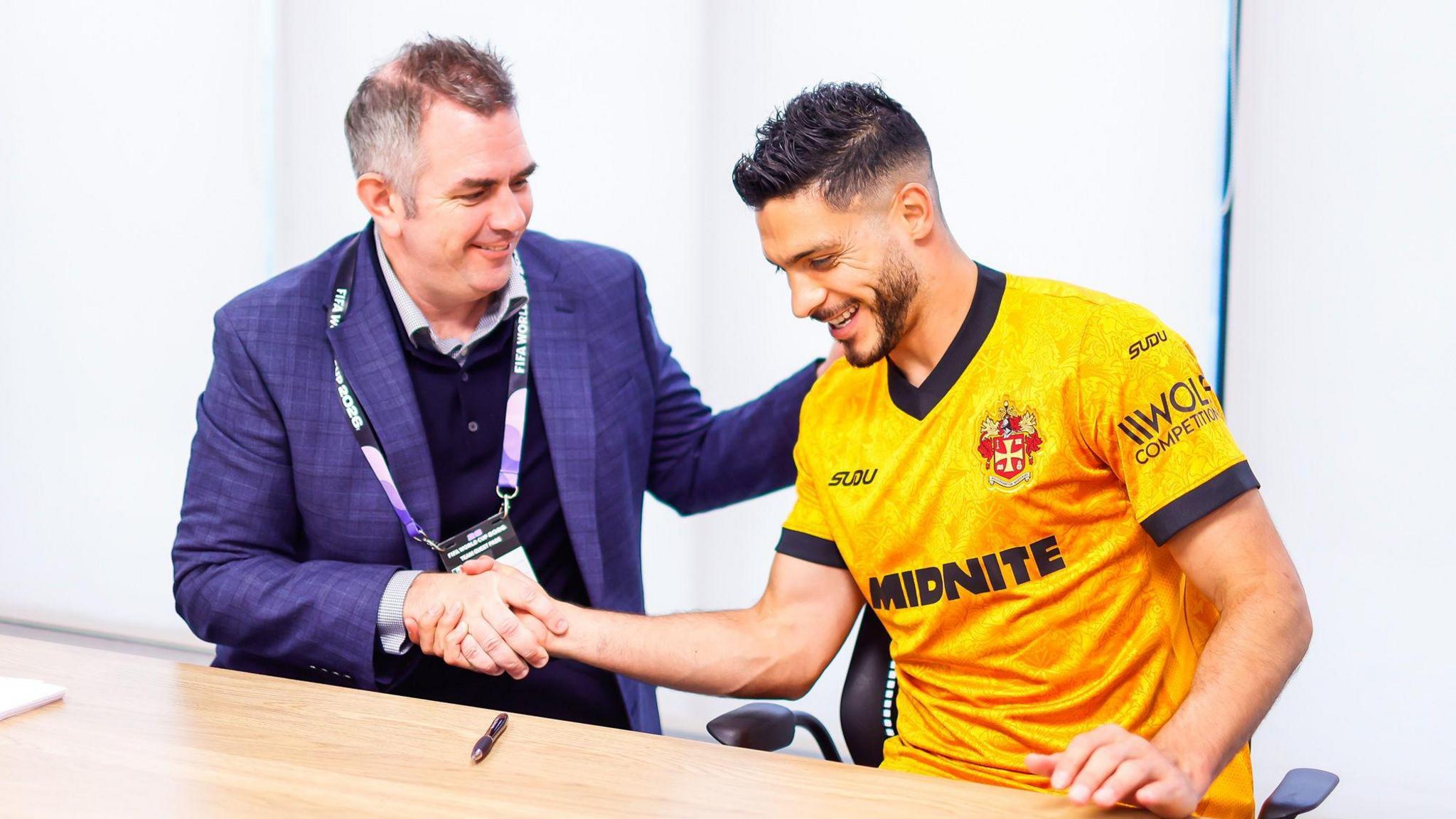 A photo of Raul Jimenez, wearing the new Wolverhampton Wanderers home kit, shaking the hand of Matt Wild as he signs a new contract with the club