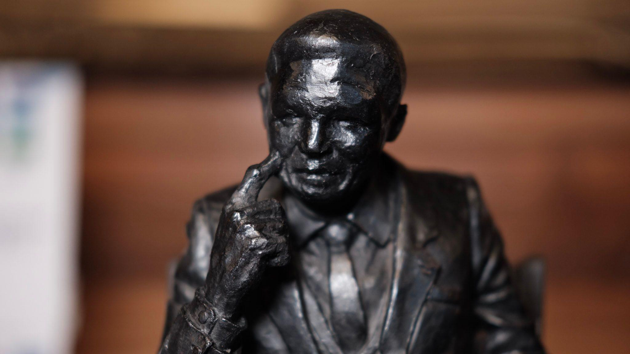 A proposed statue of Nelson Mandela. He is sitting in a chair looking thoughtful, resting a finger on his cheek.