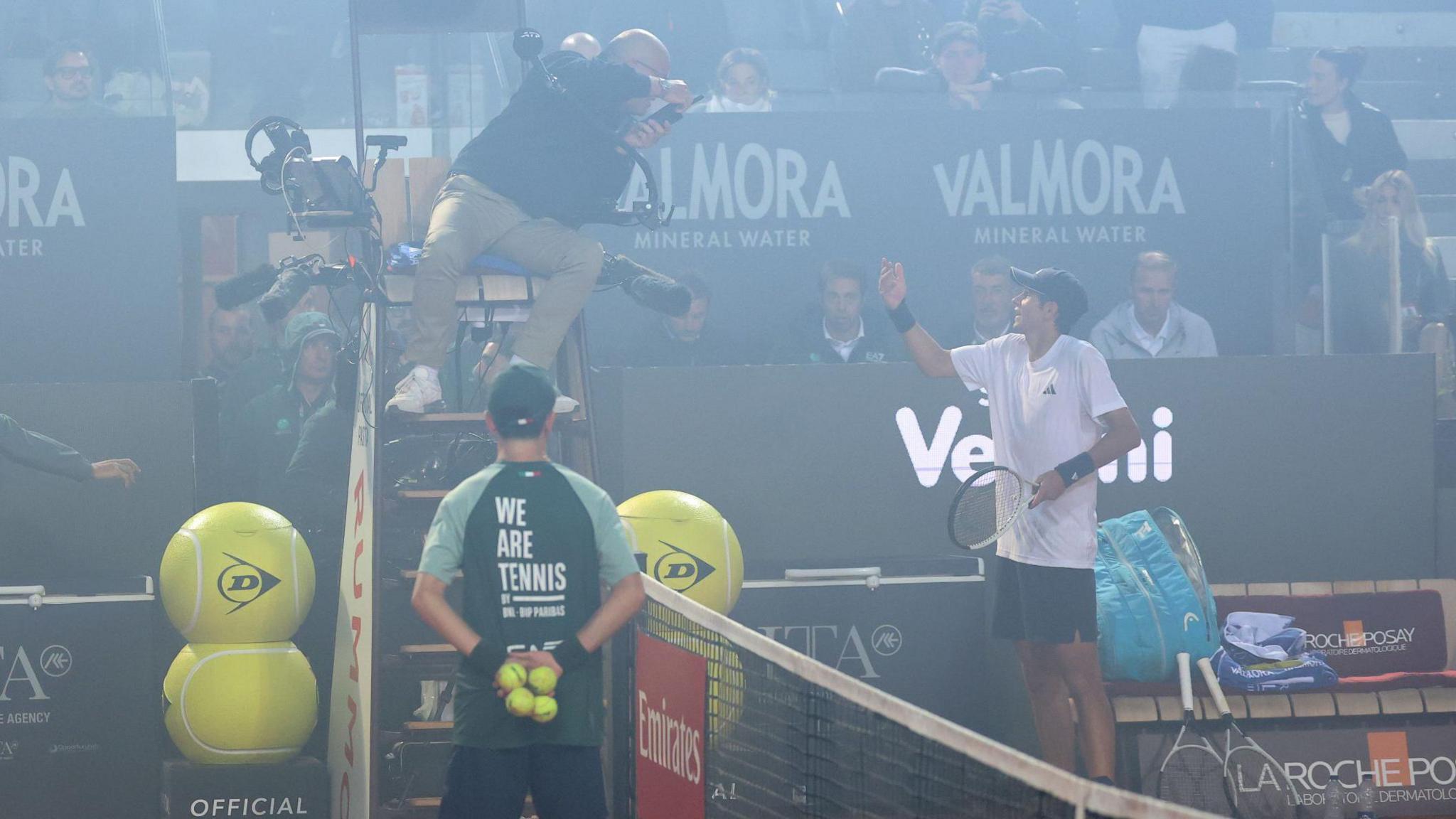 Spain's Rafael Jodar speaks with umpire Manuel Messina after smoke from the Coppa Italia final between Inter Milan and Lazio surrounds the court in his Italian Open quarter-final against Italy's Luciano Darderi