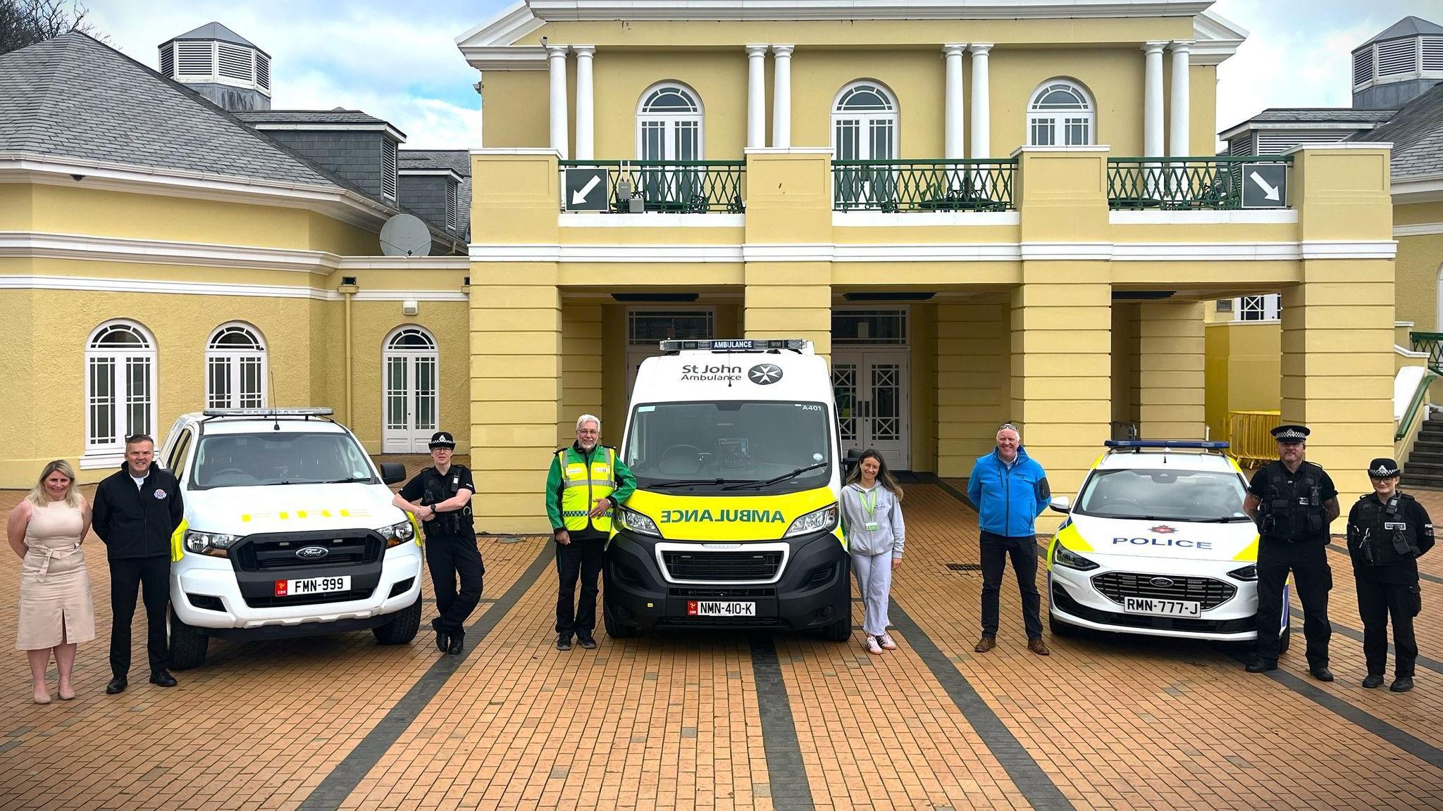 Emergency service staff and volunteers with a fire, ambulance and police vehicle outside the yellow painted Villa Marina