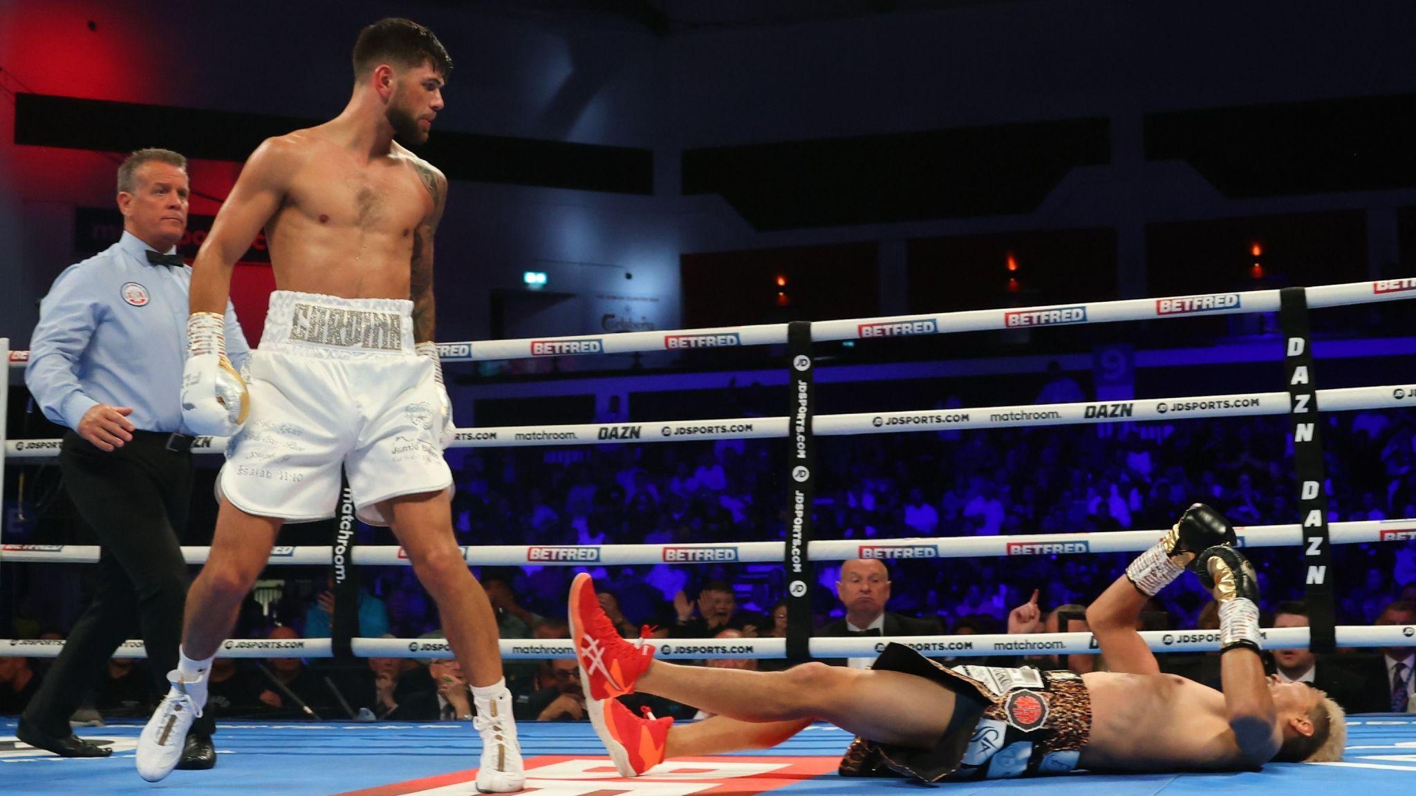 Joe Cordina stands over Kenichi Ogawa lying flat on the canvas