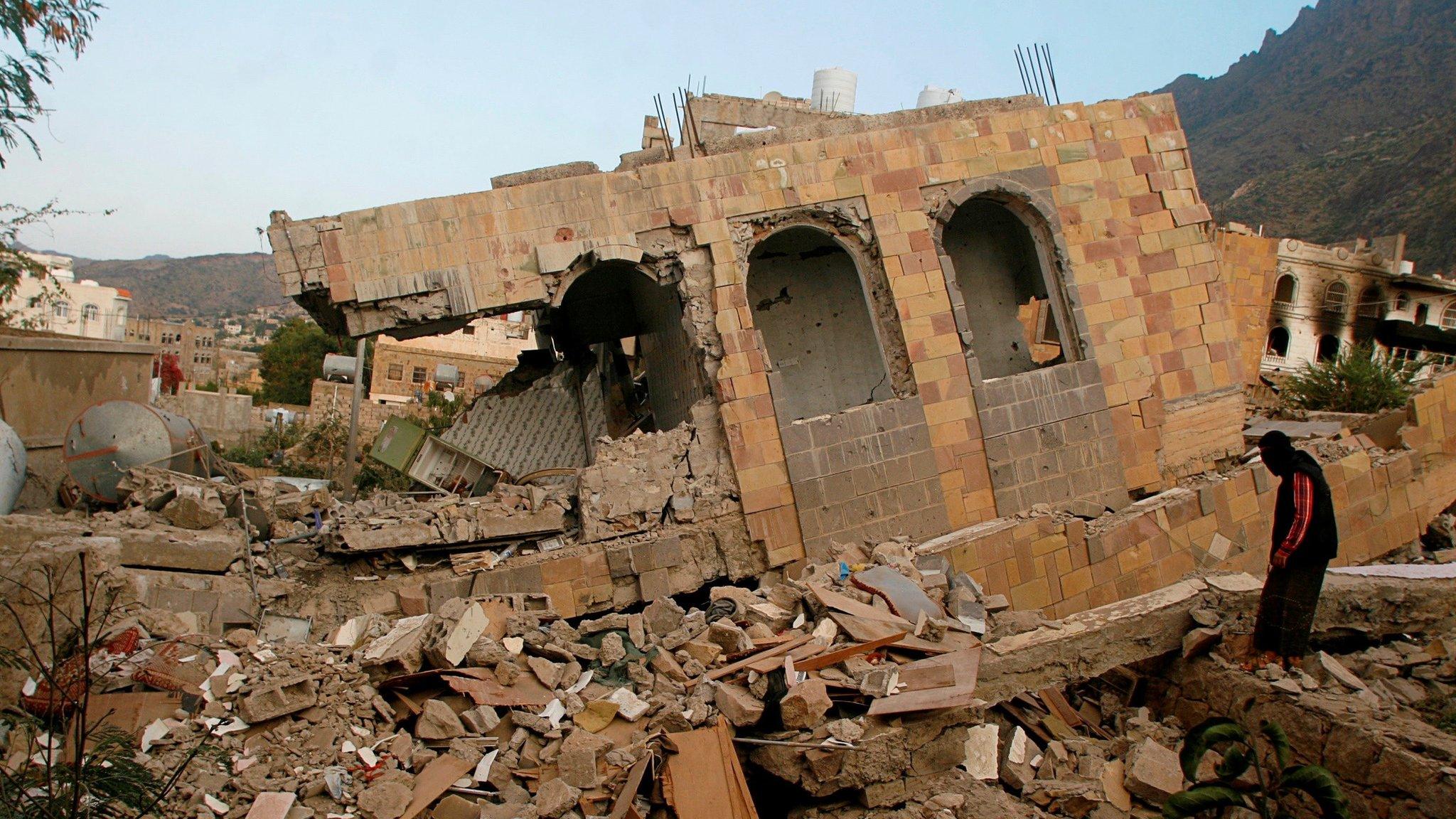 A man walks over the remains of a building destroyed by fighting in Taiz, Yemen (20 November 2016)