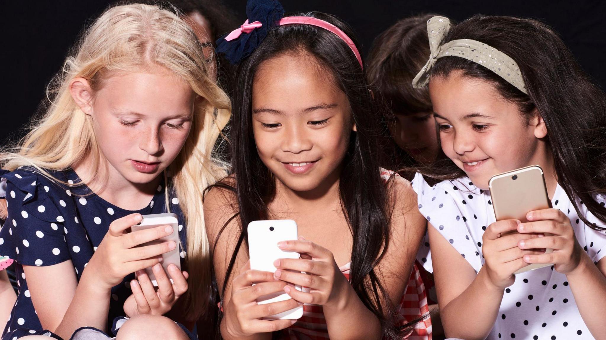 Three girls smiling with their phones in their hands