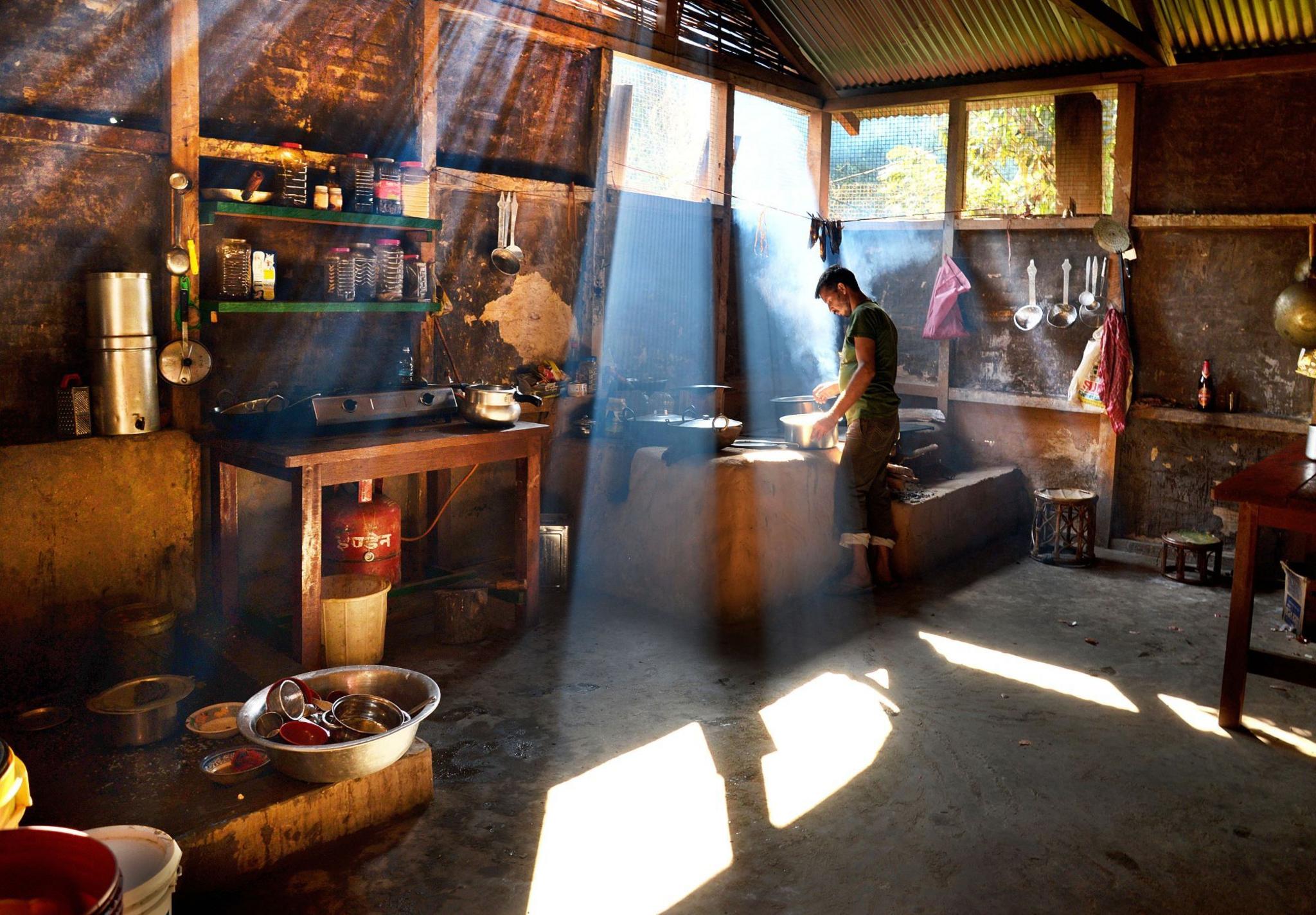 A man cooks inside a kitchen bathed in light