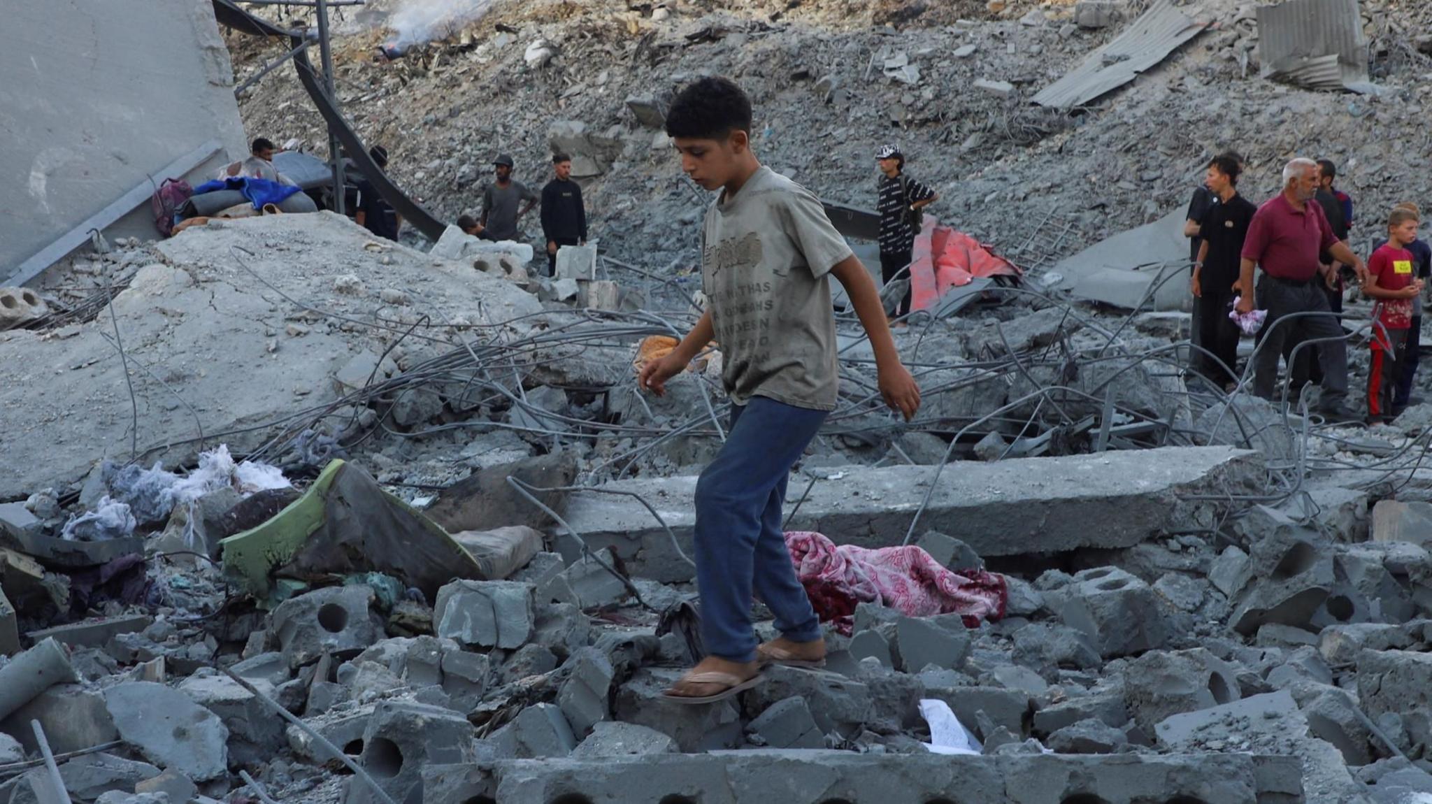 Palestinians stand on the rubble of a building sheltering displaced families near Firas market in Gaza City, which was destroyed in an Israeli air strike (24 September 2025)