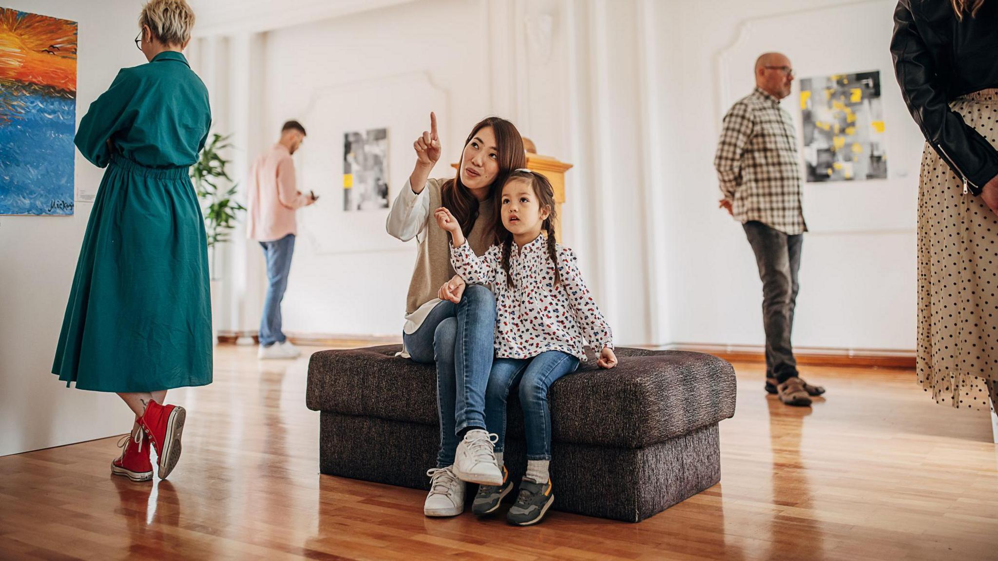 A child and woman sitting down in an art gallery