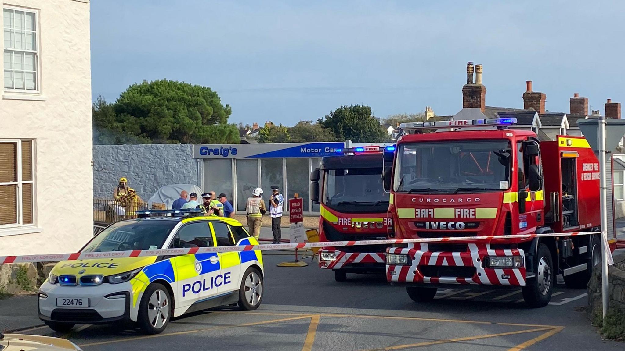 Two fire vehicles and a police car outside a garage