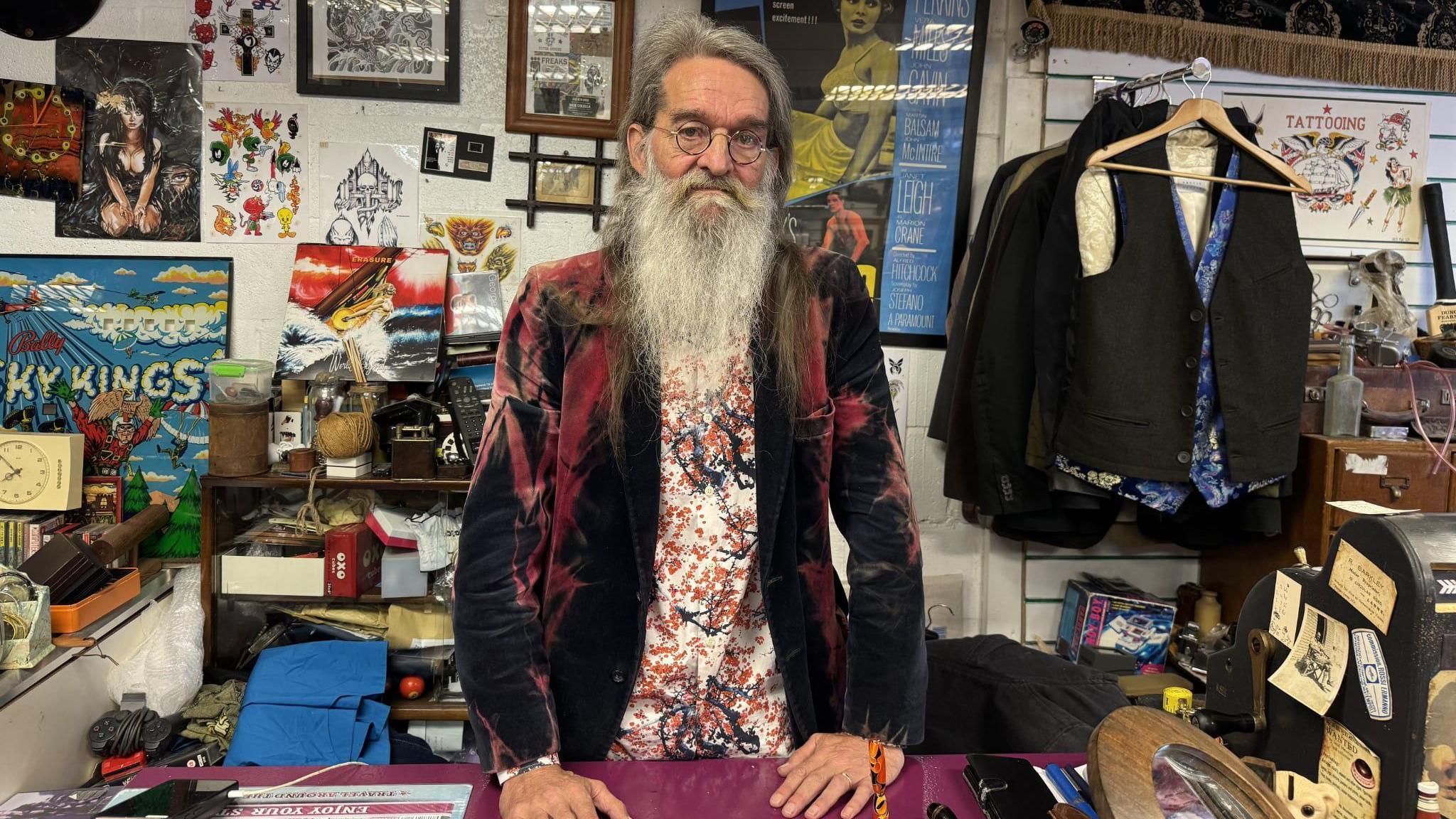 Rob Davies standing in his shop in front of several items