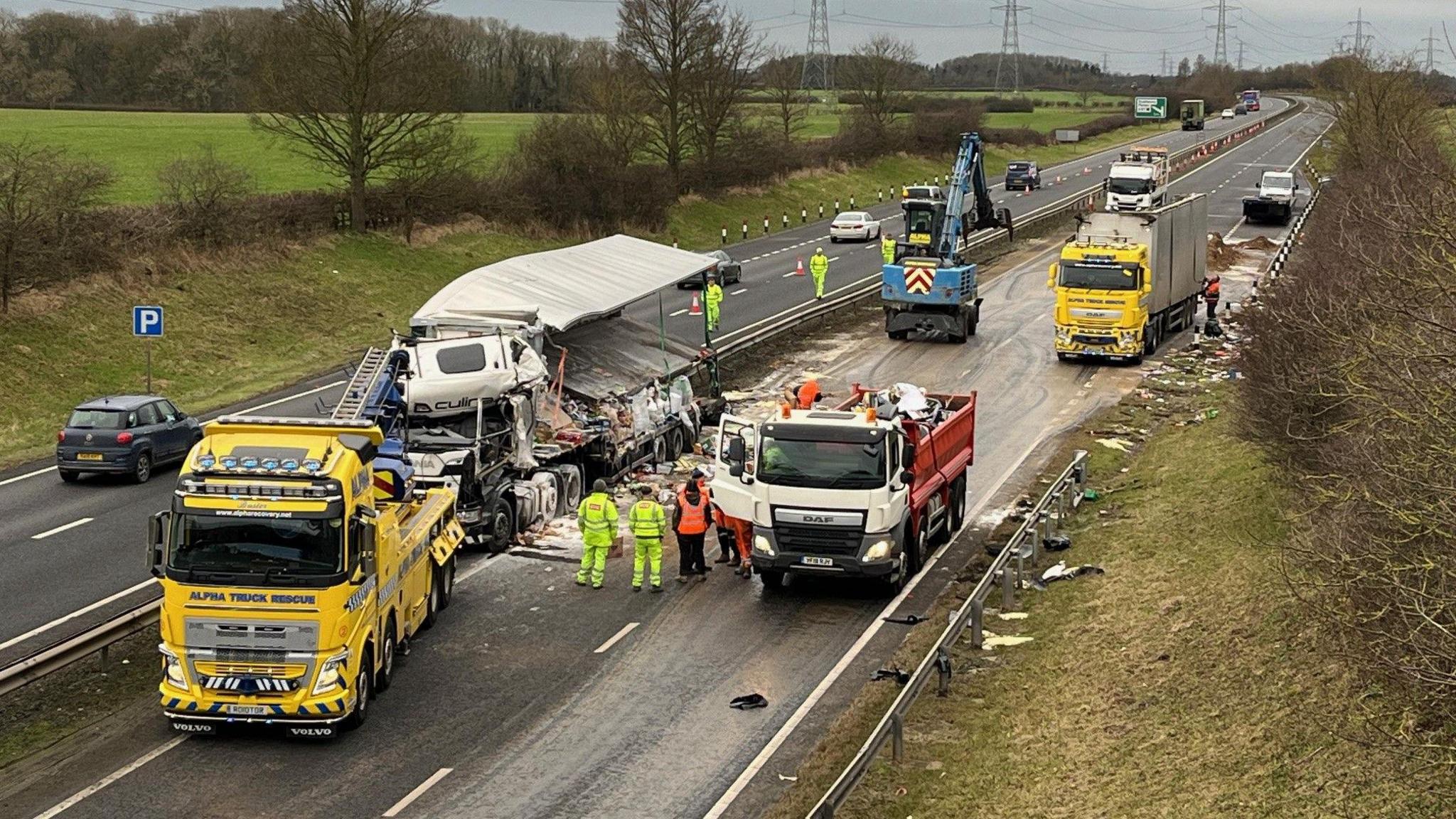 A clean-up operation takes place on the A19. A lorry has hit the middle barrier and debris is strewn across the road. A second lorry at the back also has its load spilled. There is a small National Highways lorry with staff in high-visibility clothing inspecting the area.
Some vehicles are travelling in the left southbound lane, with the rest of the road shut.