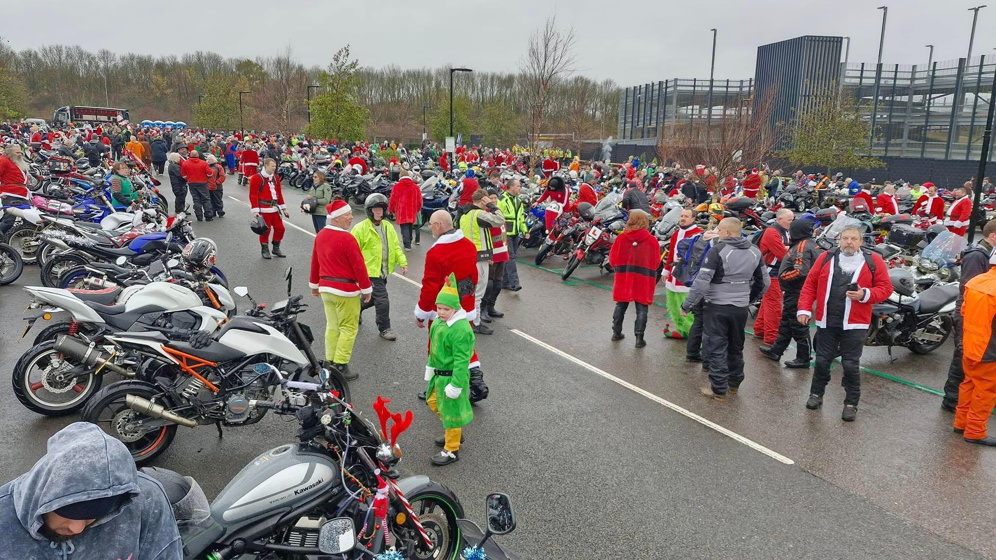 A large car park full of hundreds of motorbikes and riders dressed as Santa.