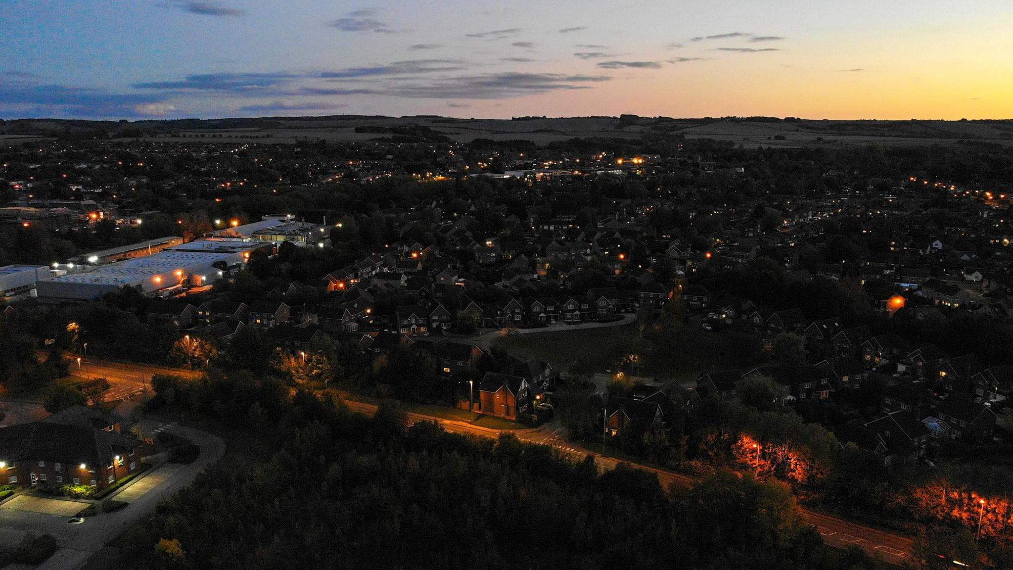 A bird's eye view of Wantage at dusk, with street lights illuminating many streets 