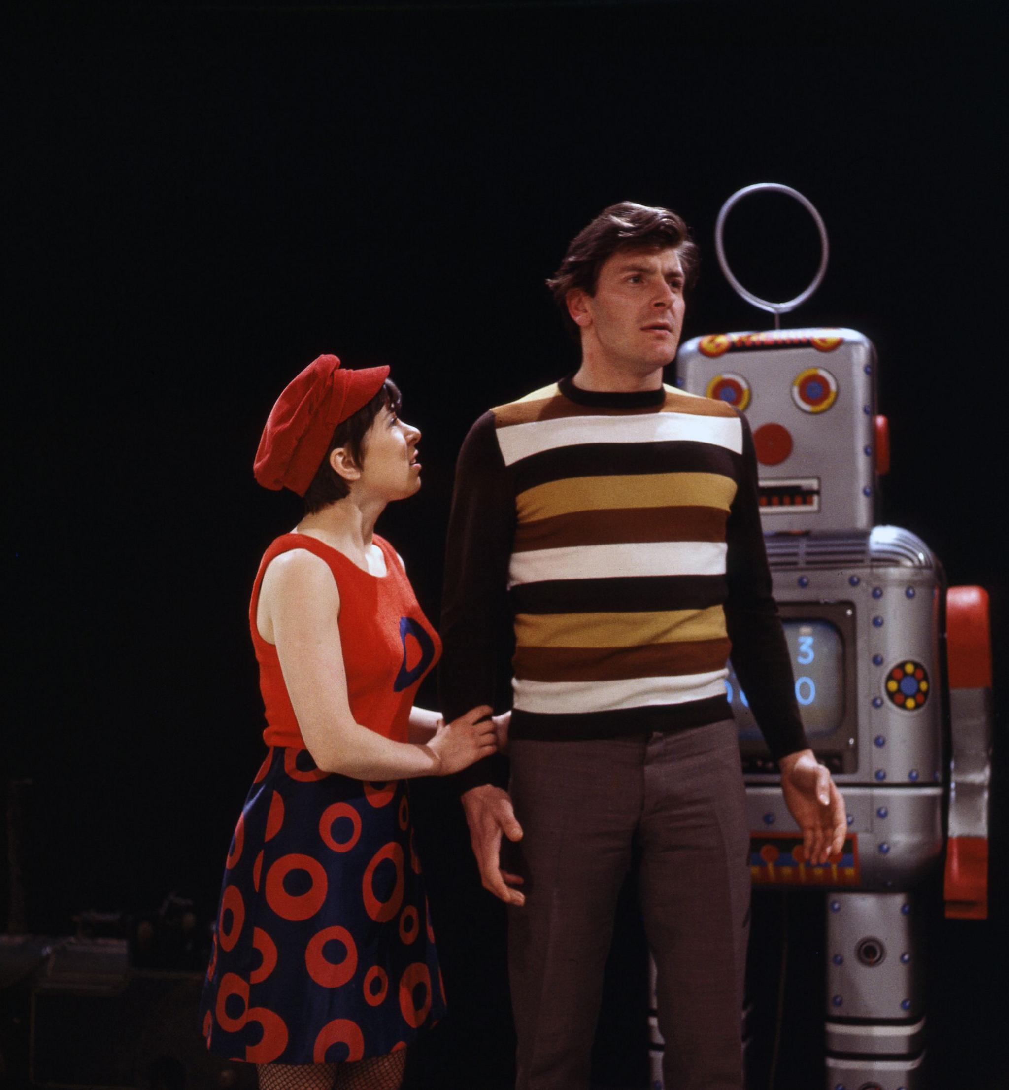 Colour photo of Jackie Lane and Peter Purves standing in front of a silver robot