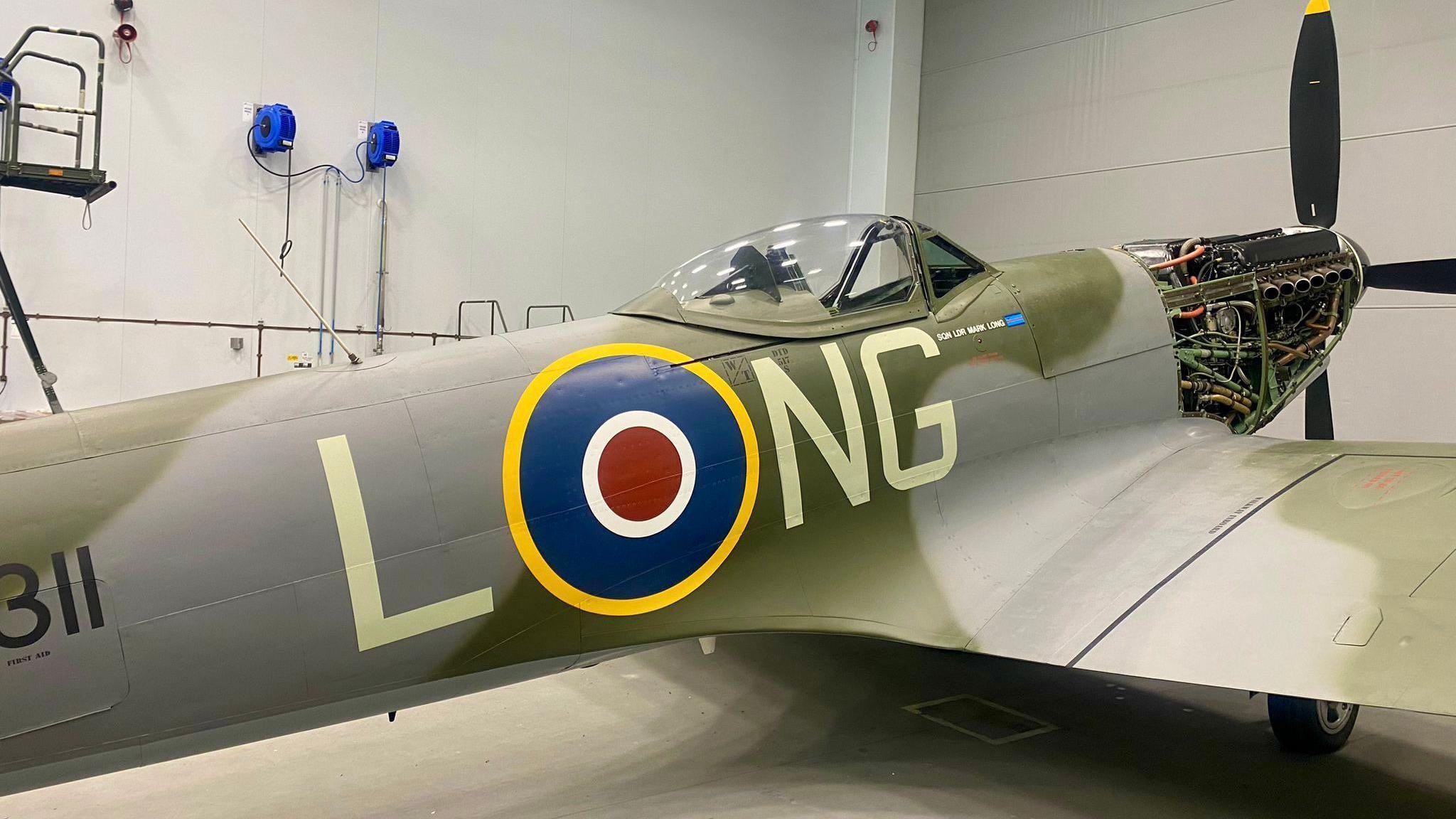 On her starboard (right) side of the camouflaged Spitfire are the letters LNG, with the RAF's circular emblem between L and NG to make it appear as LONG