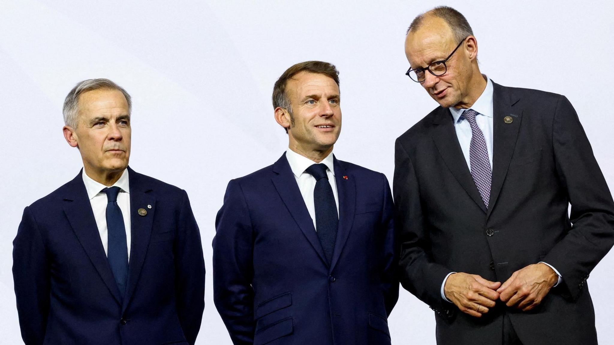 Canada's Prime Minister Mark Carney, France’s President Emmanuel Macron and Germany's Chancellor Friedrich Merz stand together, as they attend a family photo event, on the opening day of the G20 Leaders' Summit at the Nasrec Expo Centre in Johannesburg, South Africa.