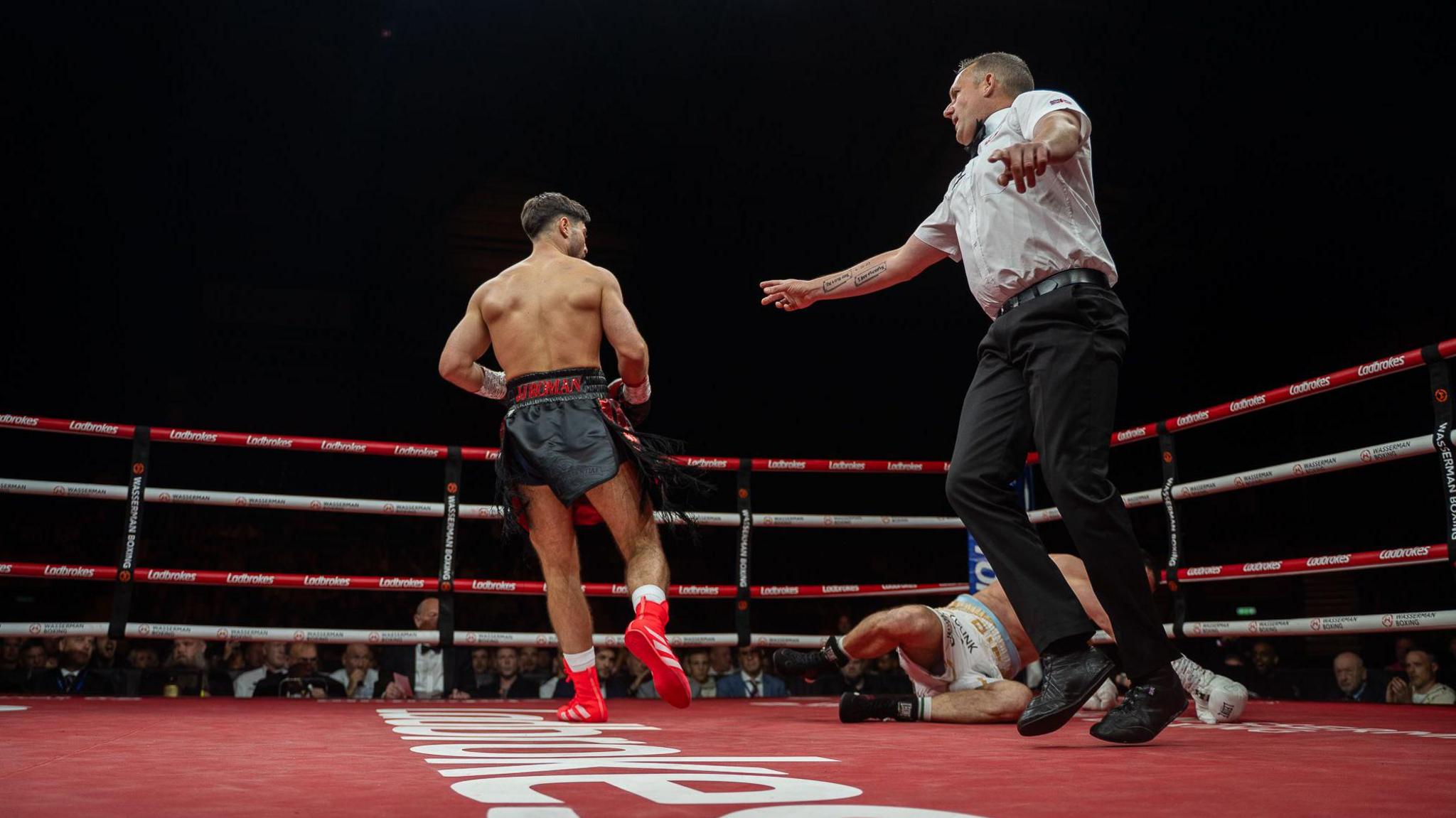 The referee waves away Josh Kelly after he knocks down Flavius Biea