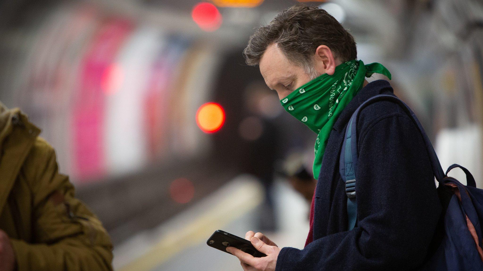 Commuter on the London Underground, checking his mobile phone