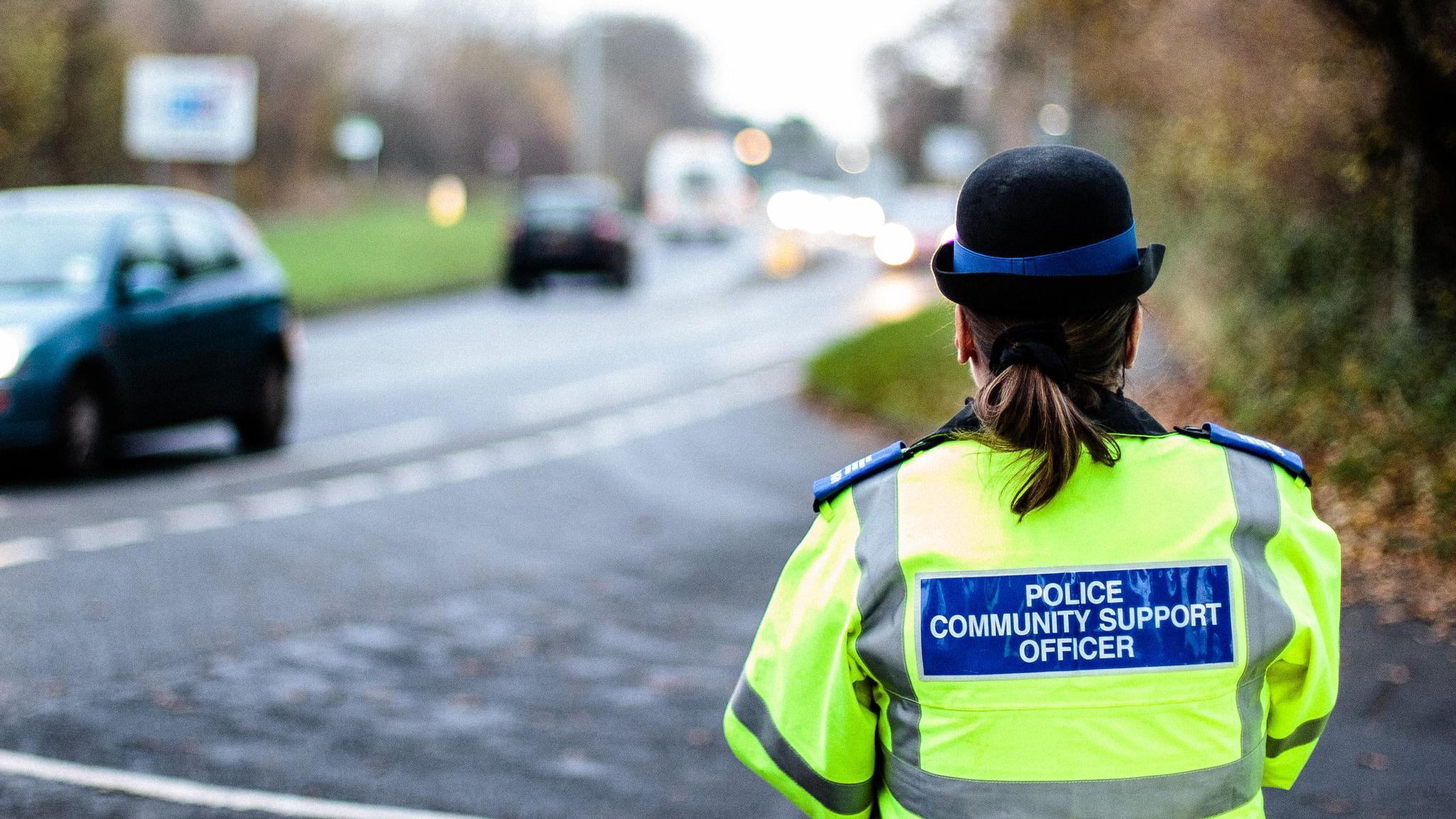 A police officer stands beside a blurred out road. 