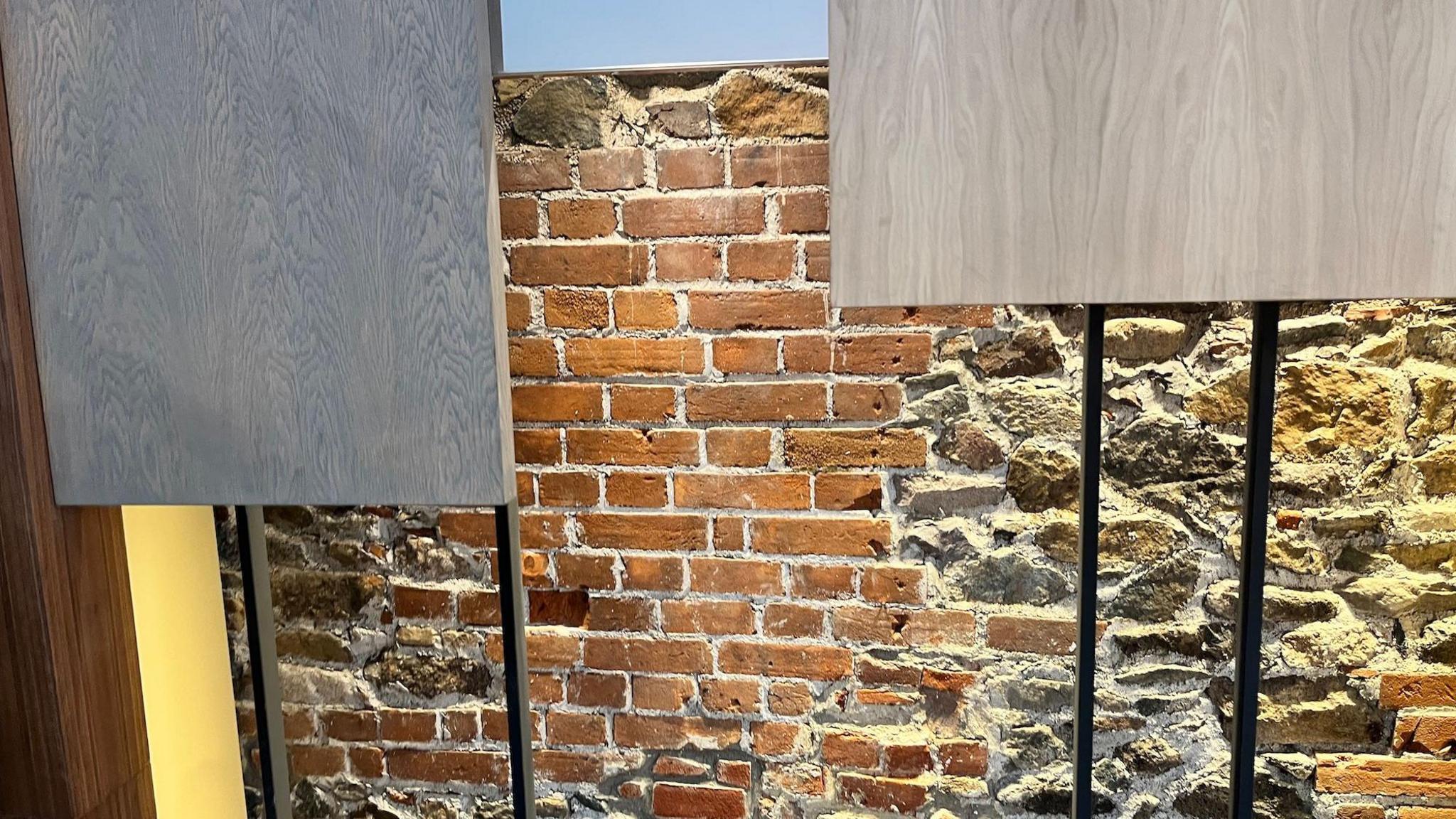 Red brickwork and granite stones are illuminated by lights behind modern panels.