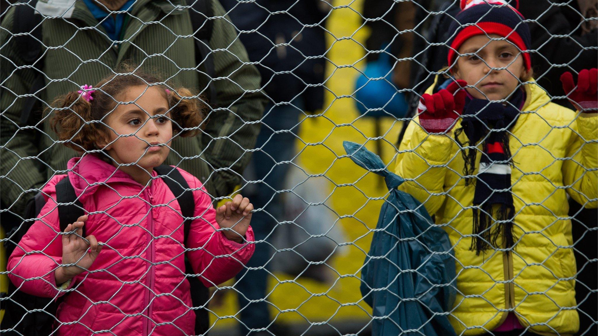 Refugees and migrant children look through a border fence after they crossed the Slovenian-Austrian border, near the village of Spielfeld, Austria (16 February 2016)