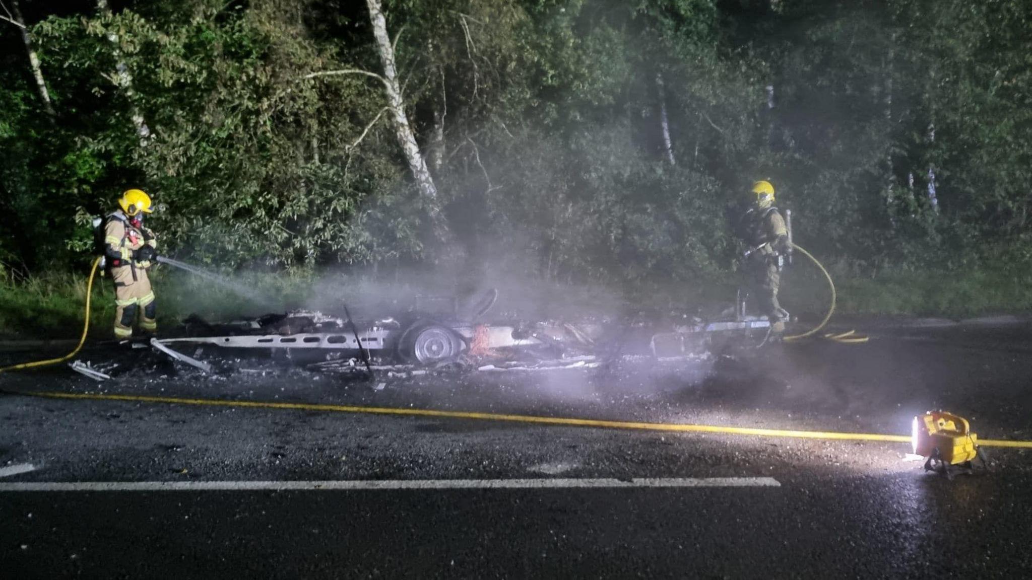 Firefighters using hosereel jets either side of the wreckage