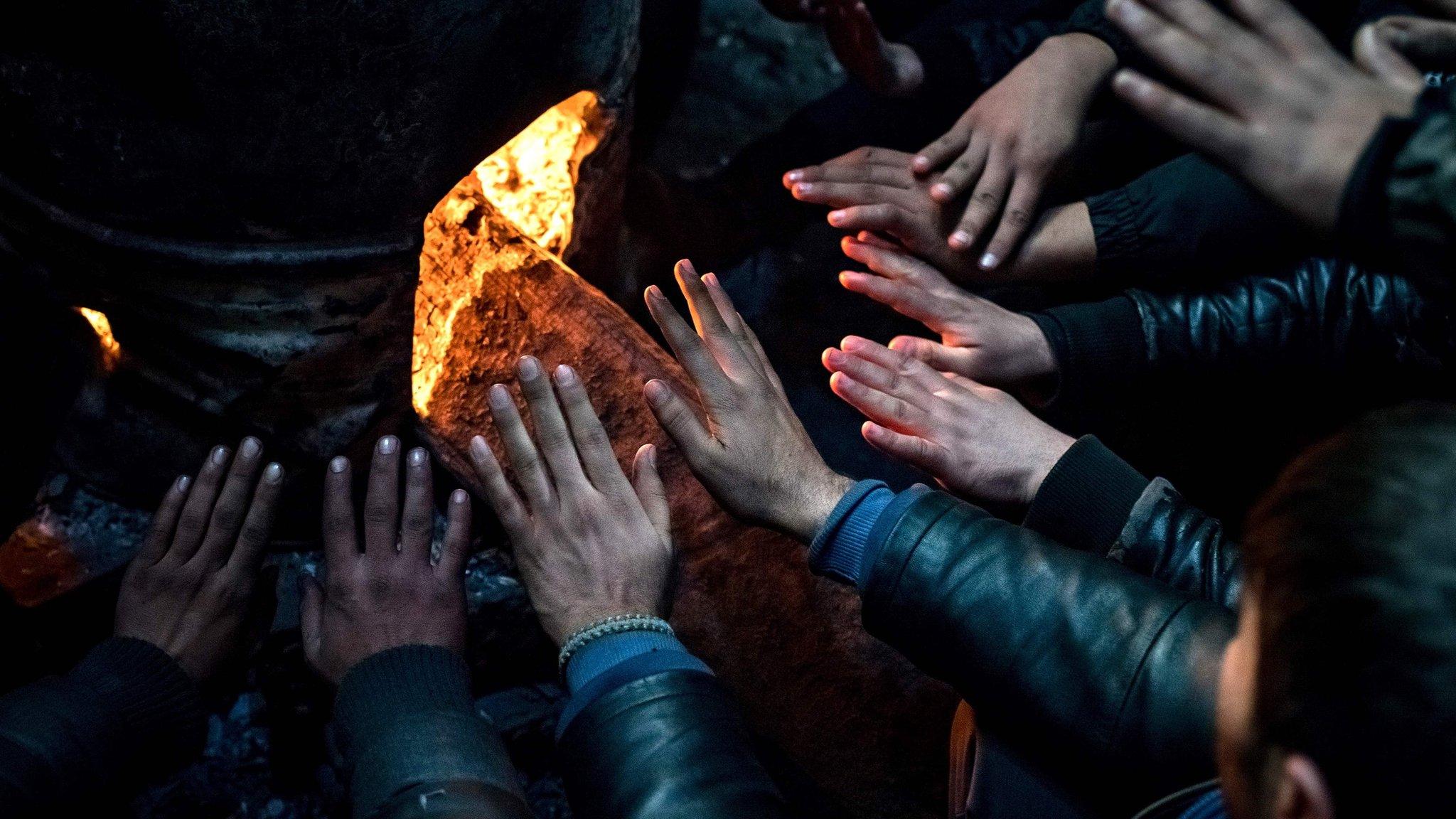 Migrants warm up at a makeshift shelter at an abandoned warehouse in Belgrade on 8 December 2016