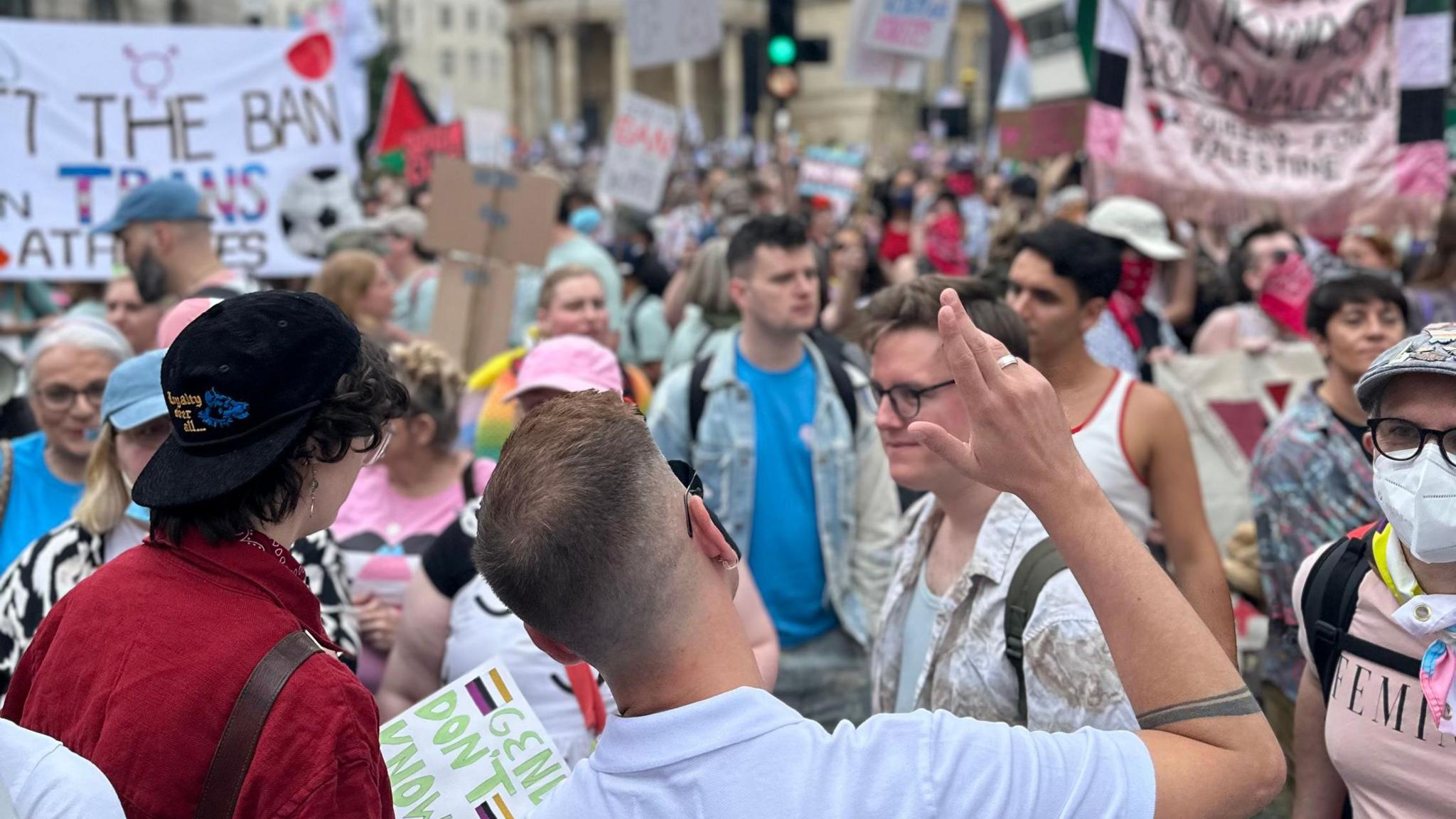 Lots of different people taking part in London Trans+ Pride. Some banners can be seen in the background
