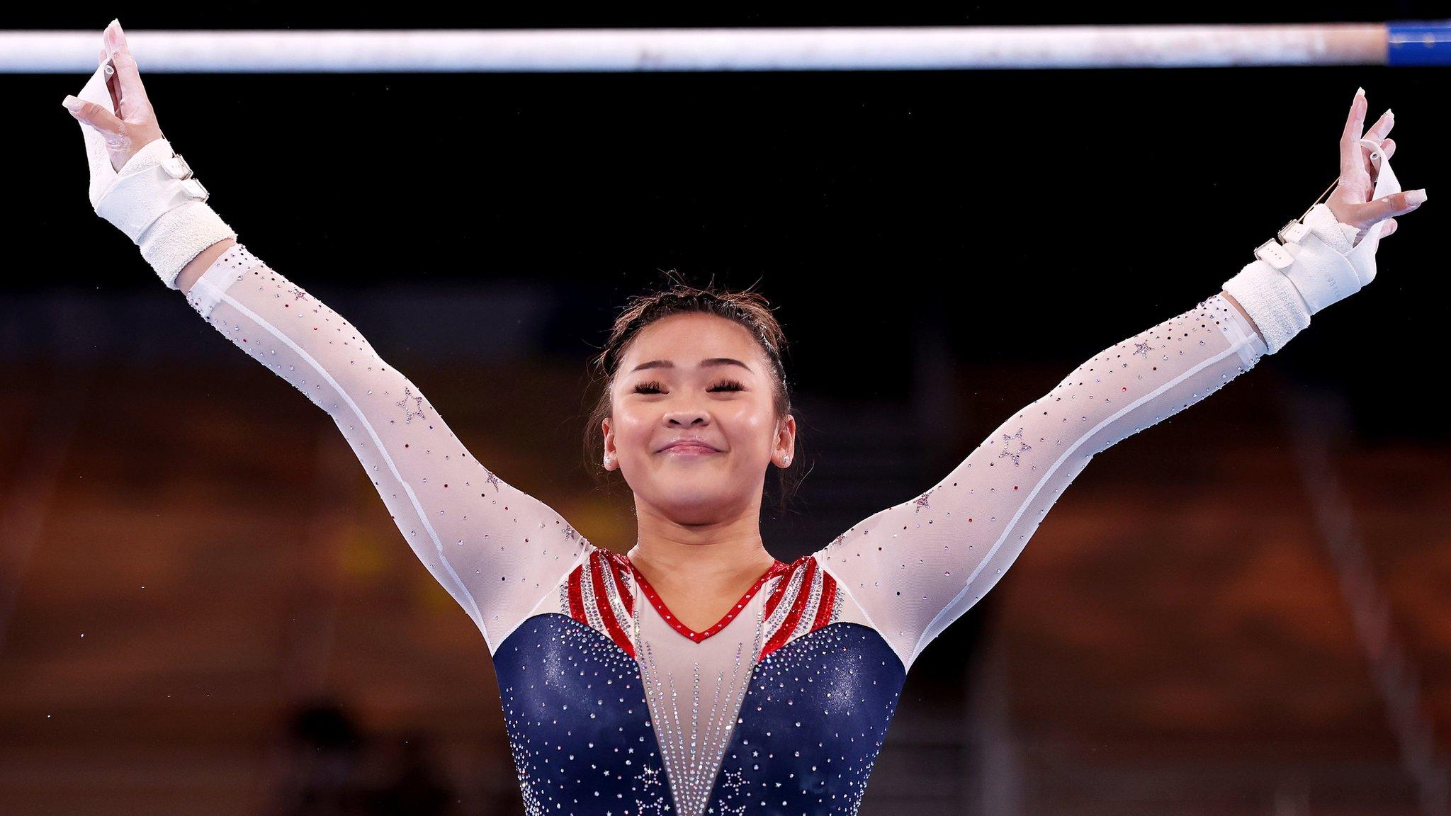 Sunisa Lee smiles with her hands in the air