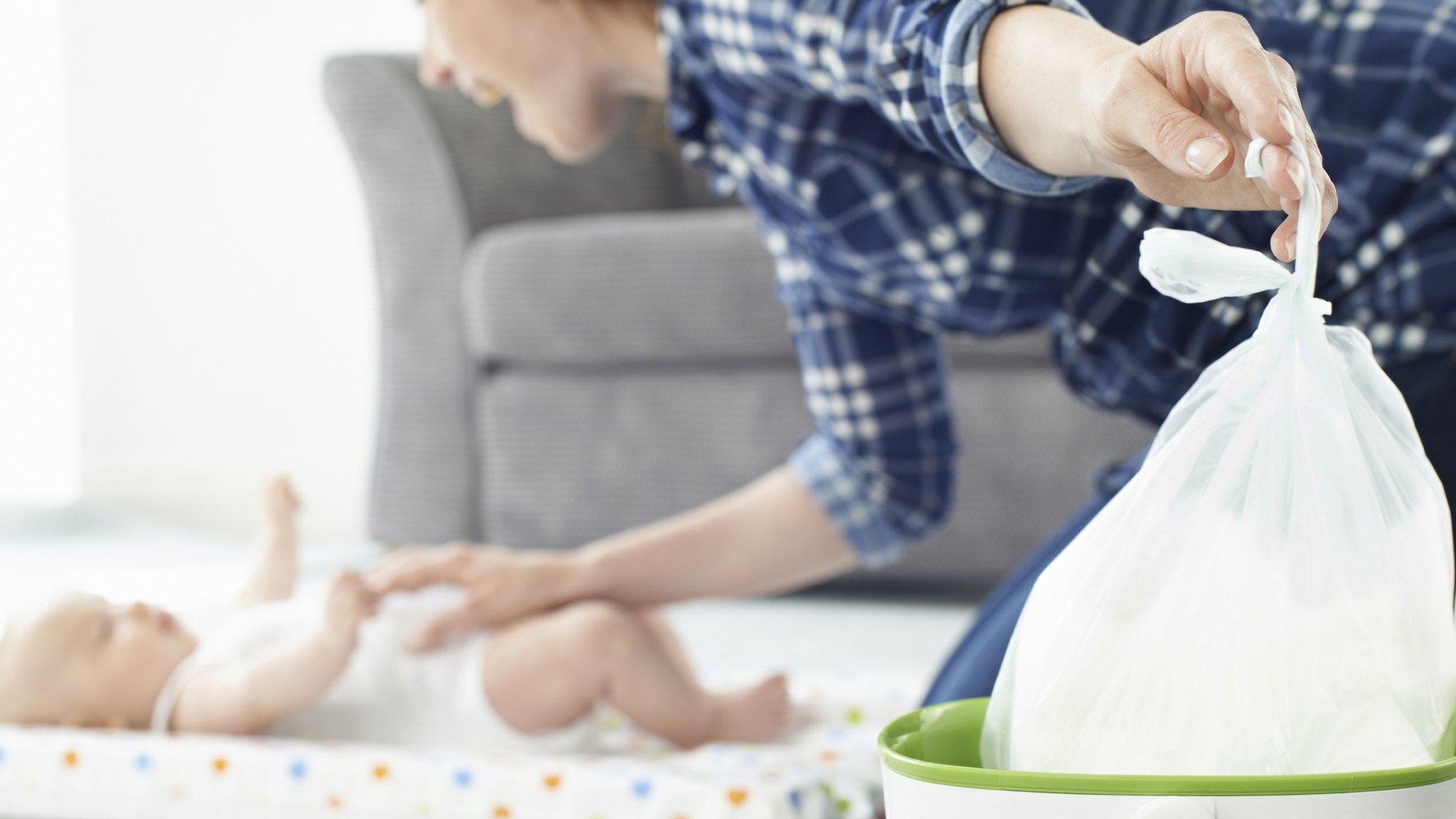 Nappy being put in a bin as a baby is changed