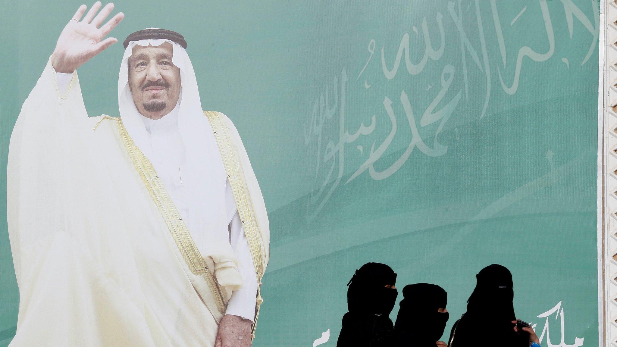 File photo showing women walking past a photo of Saudi Arabia's King Salman in Riyadh (12 February 2018)