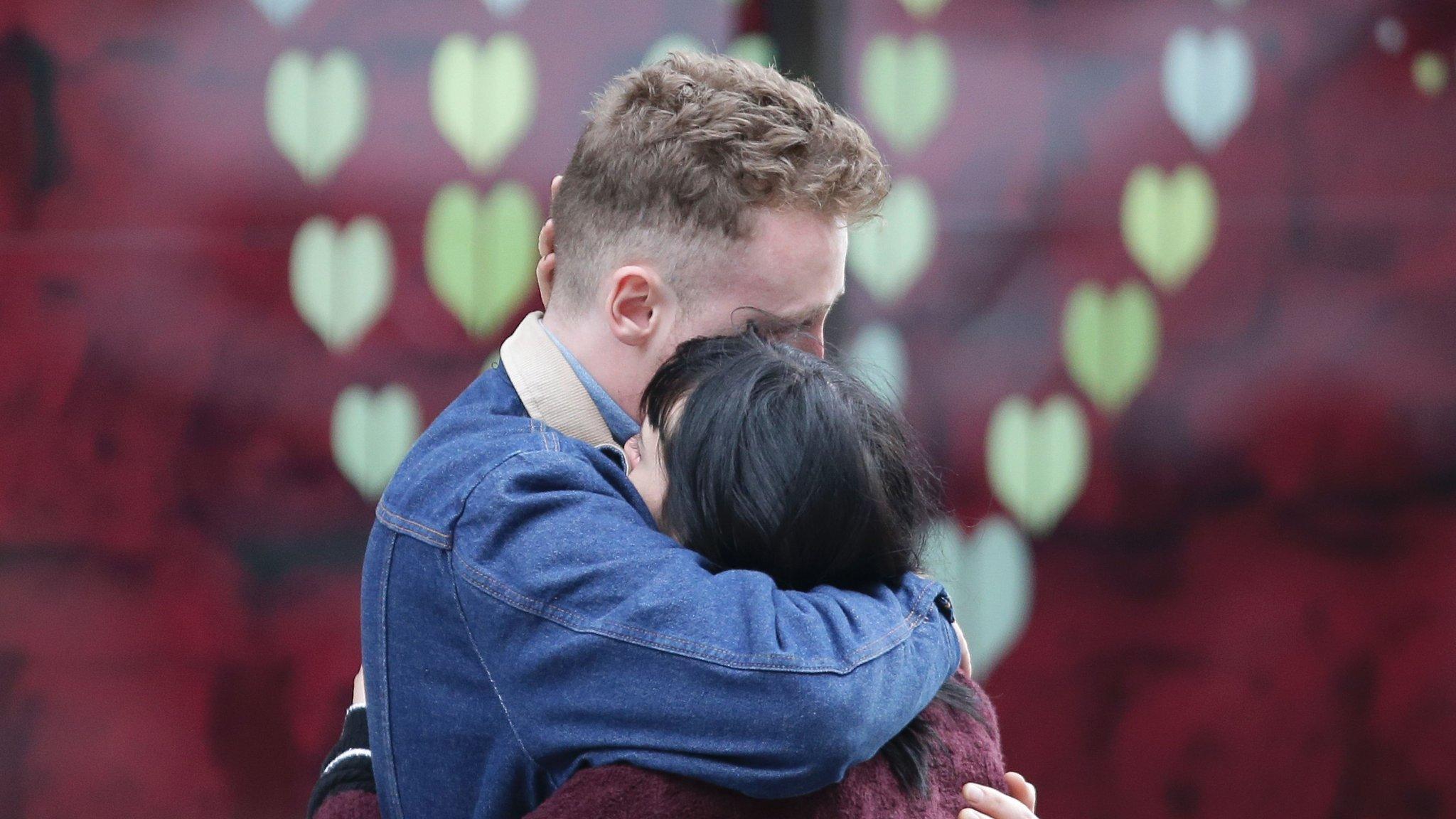 Couple hug after leaving a bunch of flowers in tribute to the victims of the terror attack