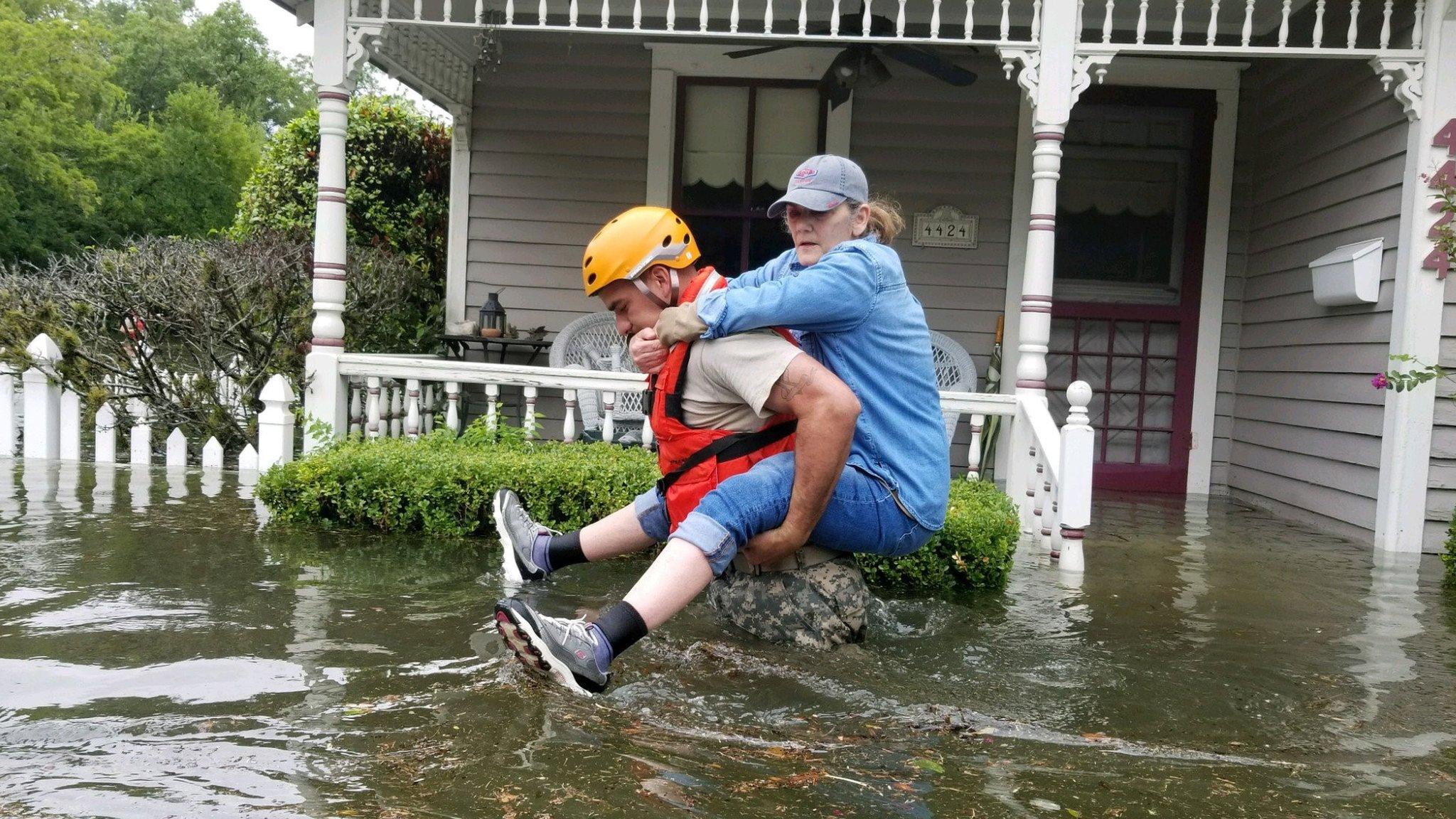 A Texas National Guard soldier carries a woman on his bank as they conduct rescue operations in flooded areas around Houston, Texas, U.S., August 27, 201