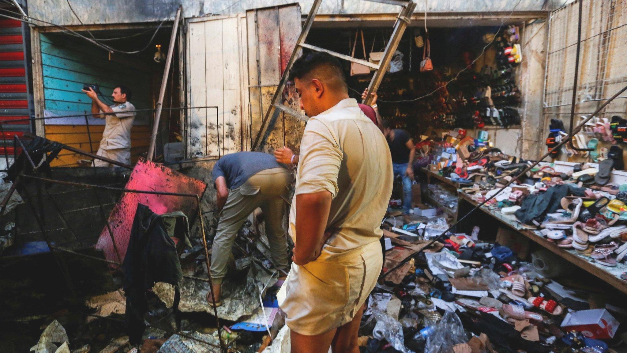 Iraqi security forces inspect the scene of a bombing in Sadr City, Baghdad (19 July 2021)