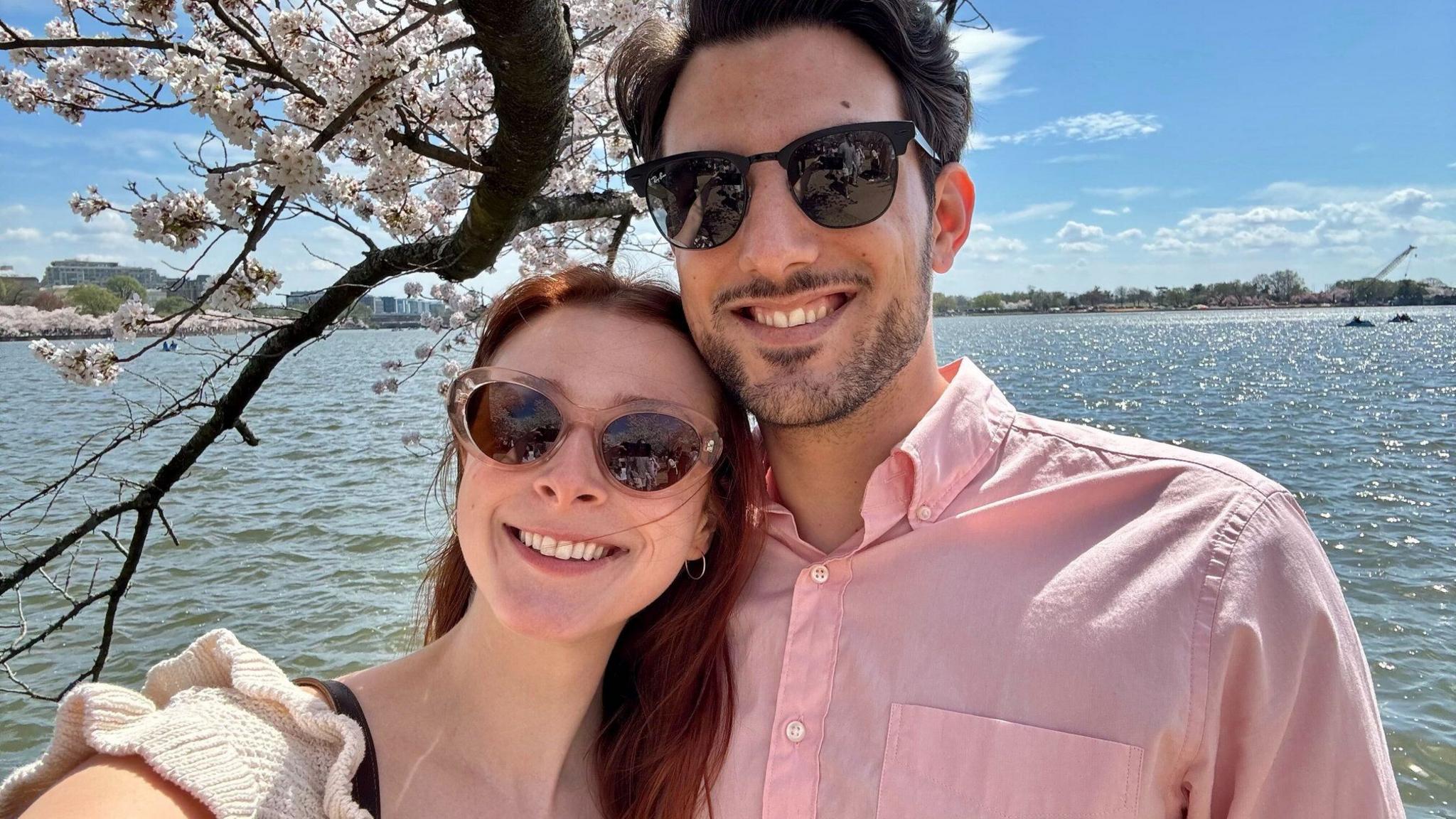 Yaron Lischinsky and Sarah Milgrim, both wearing sunglasses and smiling, with water in the background
