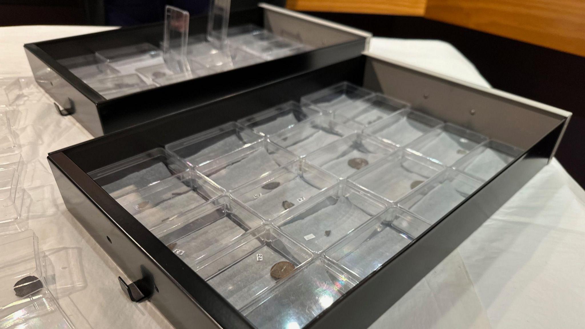 A black metal draw with 20 small plastic cases each containing a Viking coin.