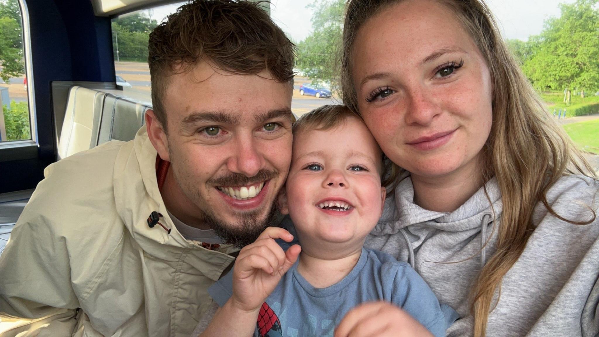 A man, woman and boy hugging 