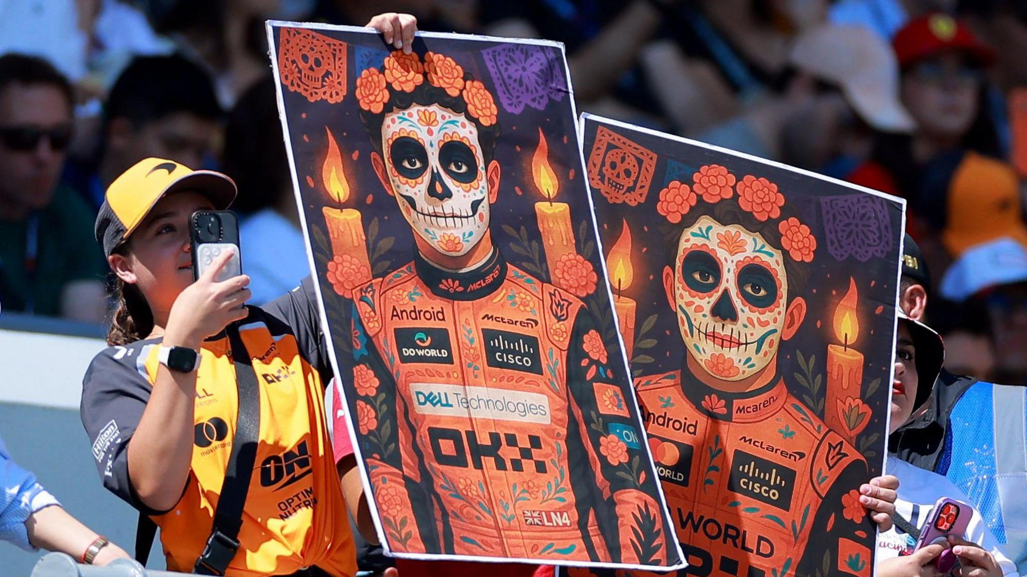 one fan is holding posters of McLaren's Lando Norris and Oscar Piastri ahead of the race.